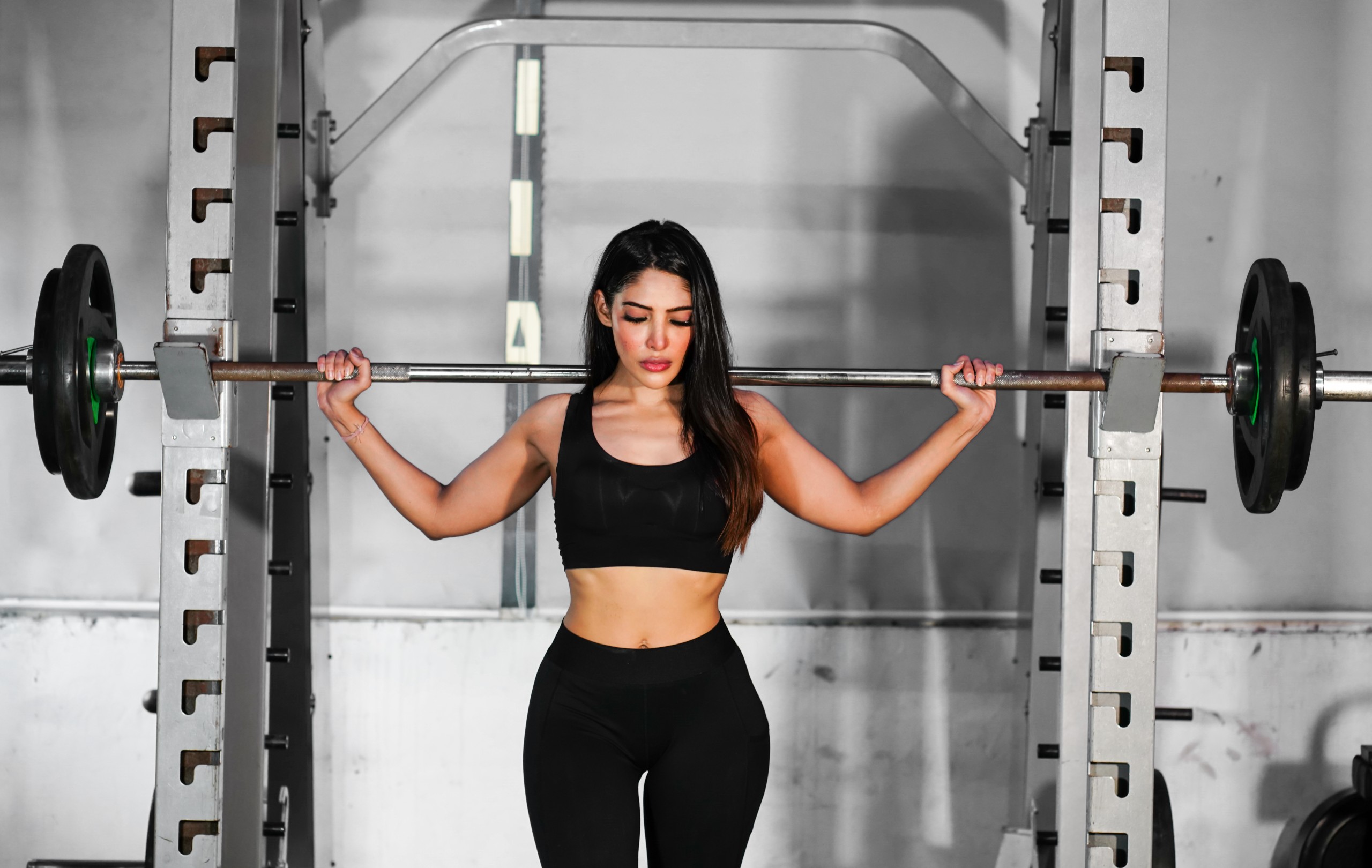 Beautiful fitness woman lifting barbell