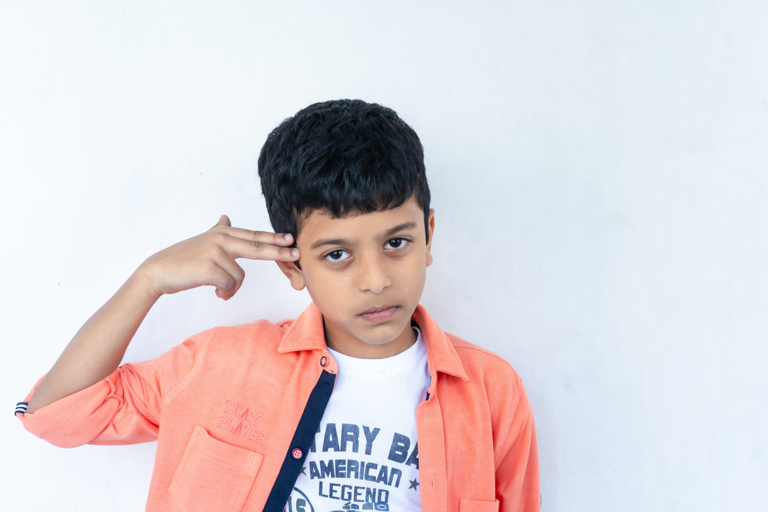 Boy holding a finger gun on his head