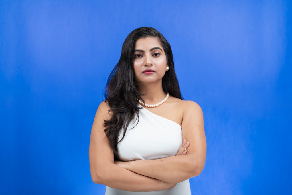 Confident angry young woman with crossed arms facing towards the camera ...