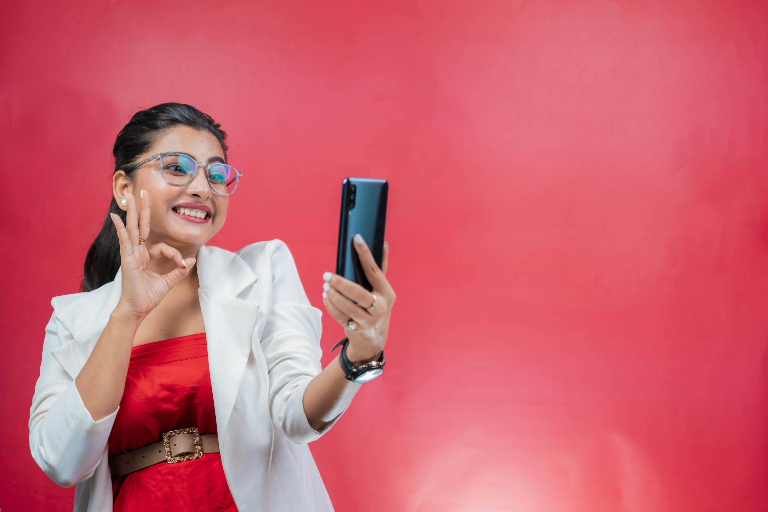 Happy young woman smiling and looking towards the phone and making OK gesture