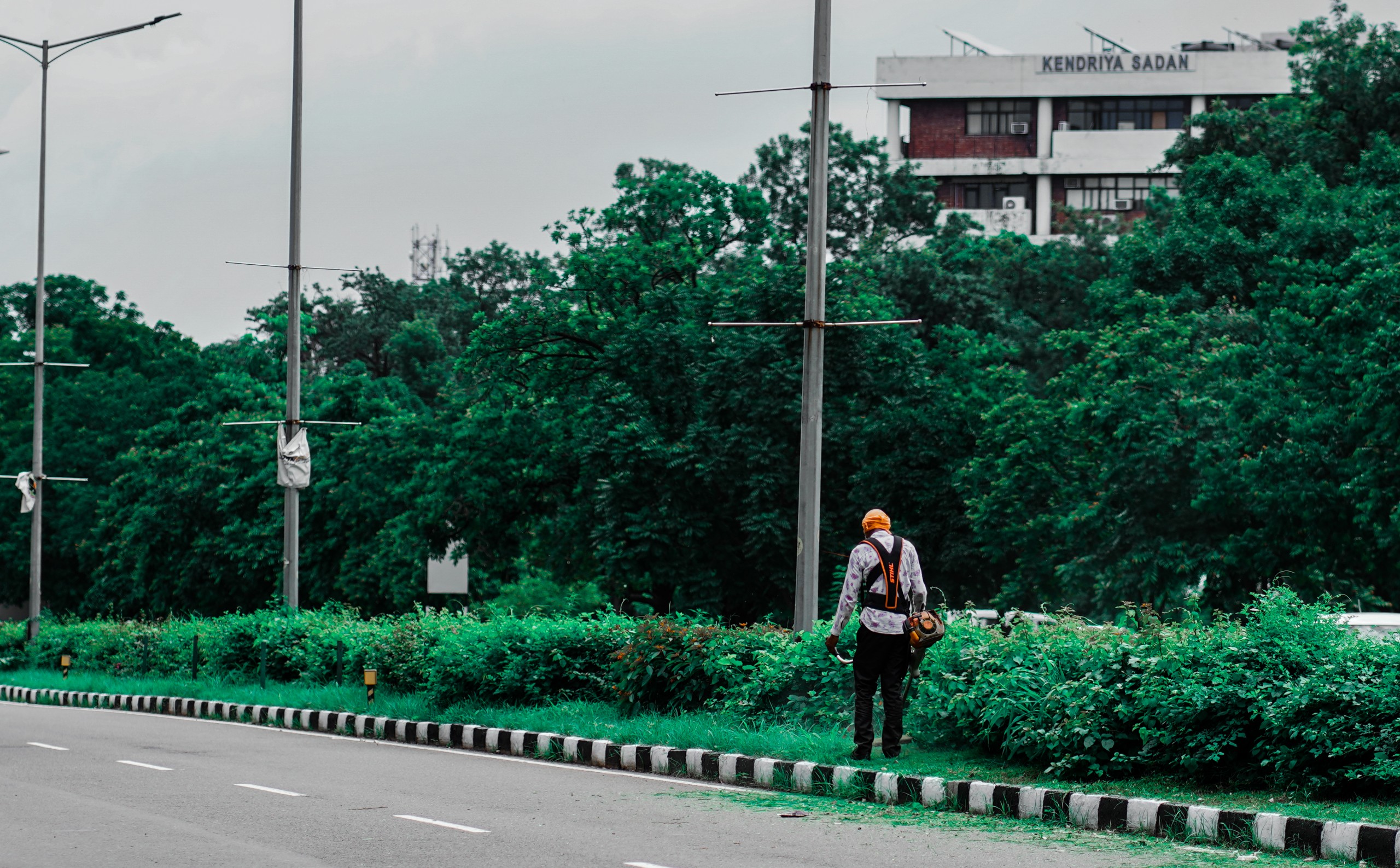 Road landscaper cutting grass along the highway using string lawn trimmer