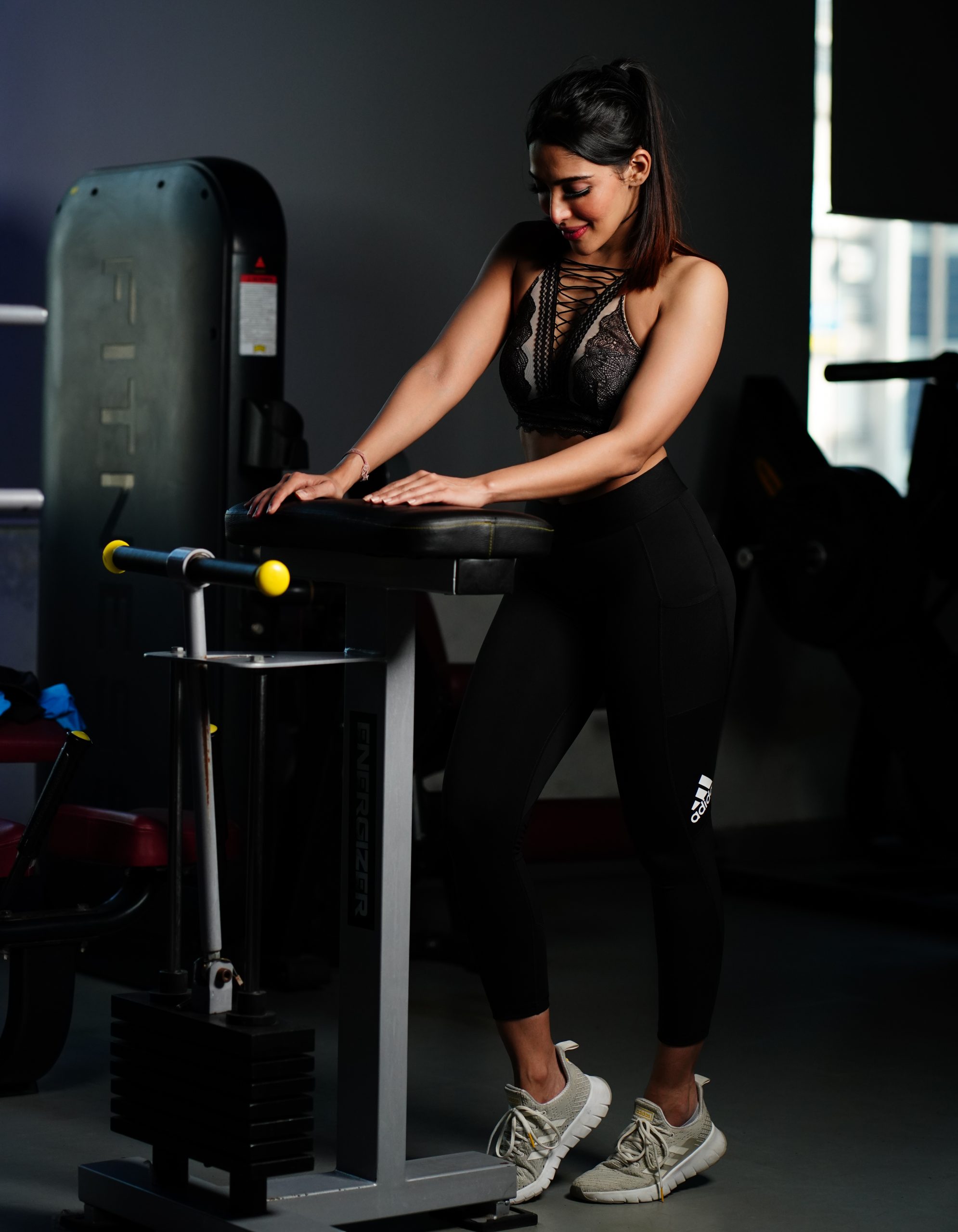 Slim girl standing next to a gym equipment