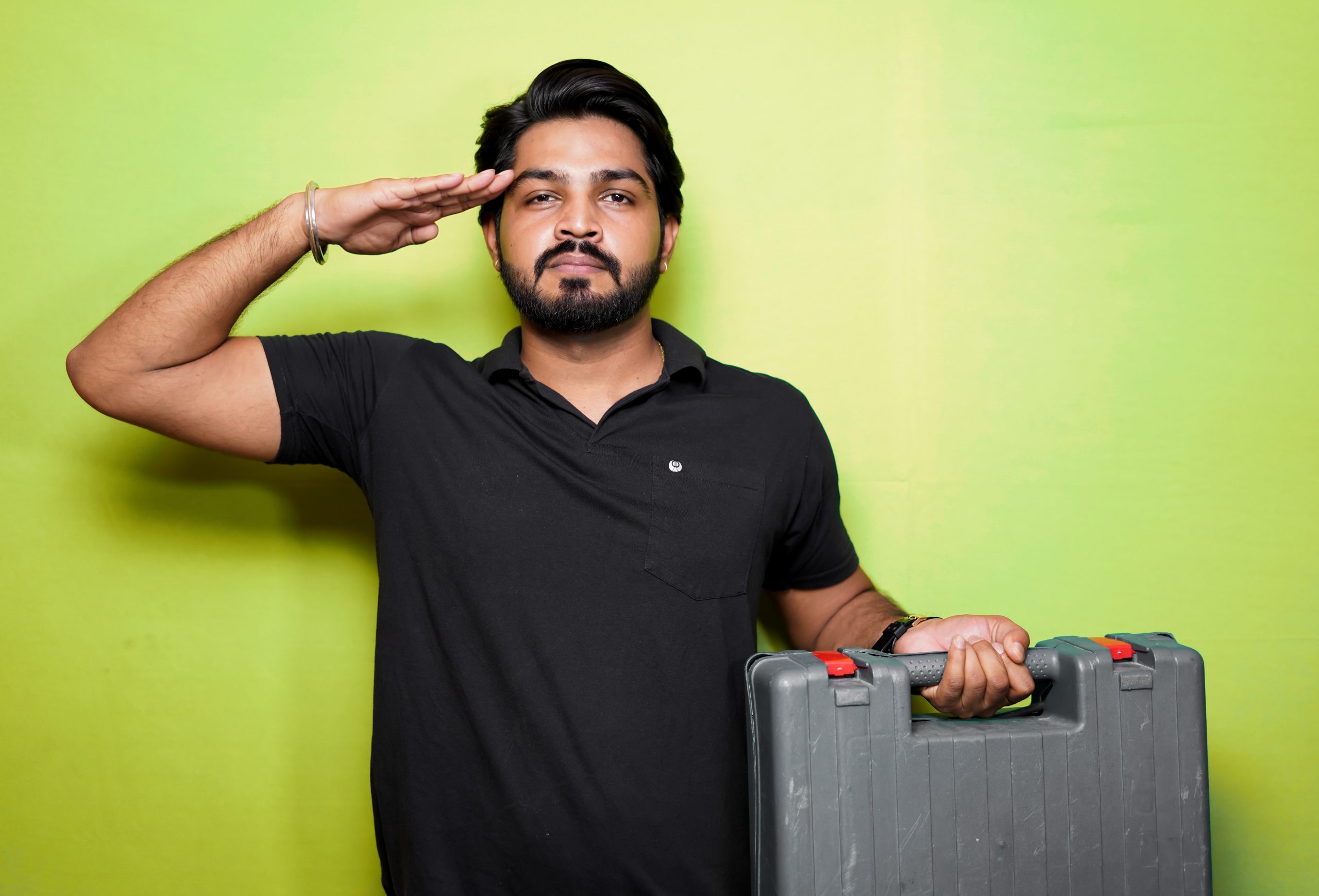 A boy saluting with tool kit