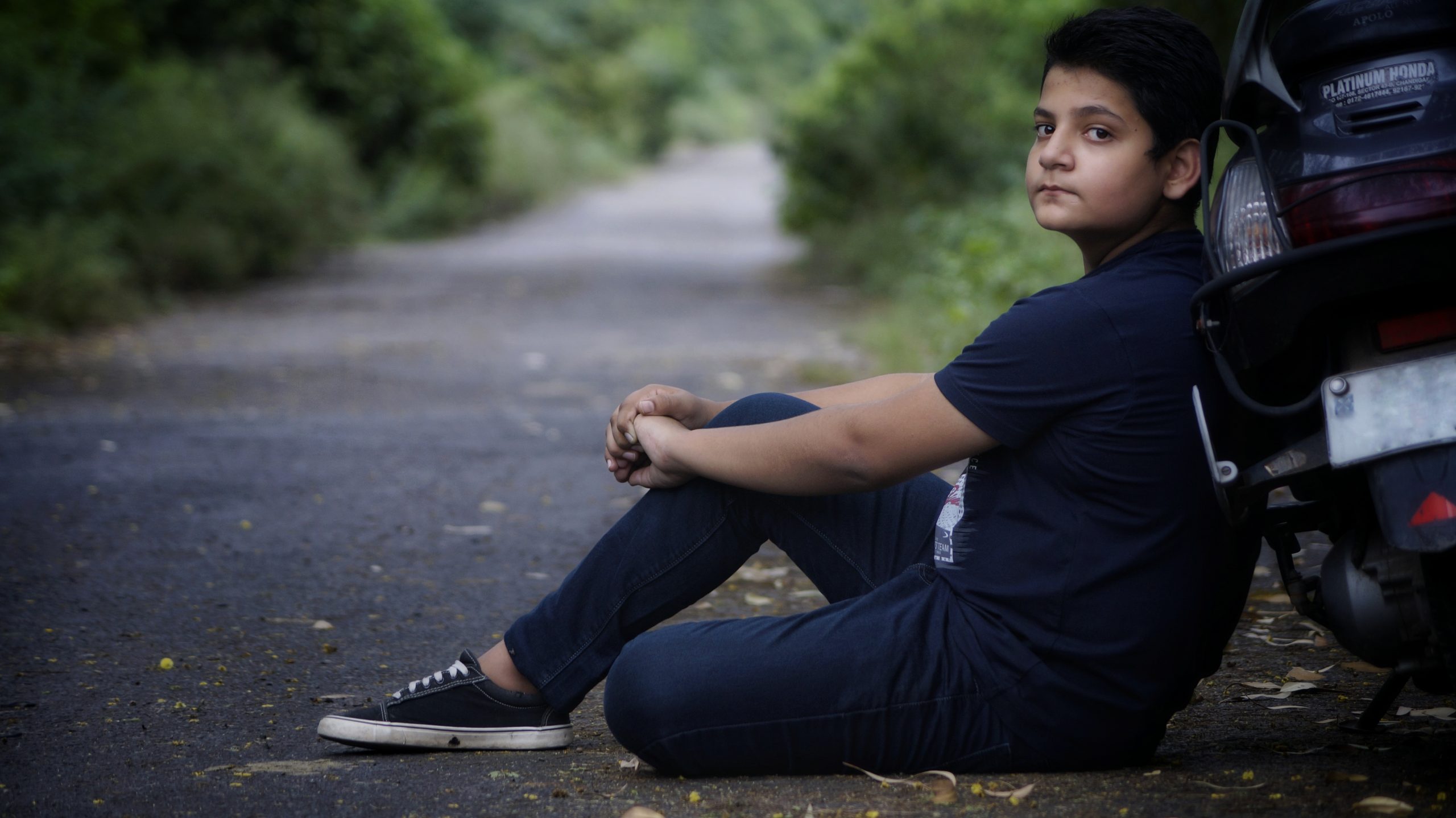 A boy sitting beside road