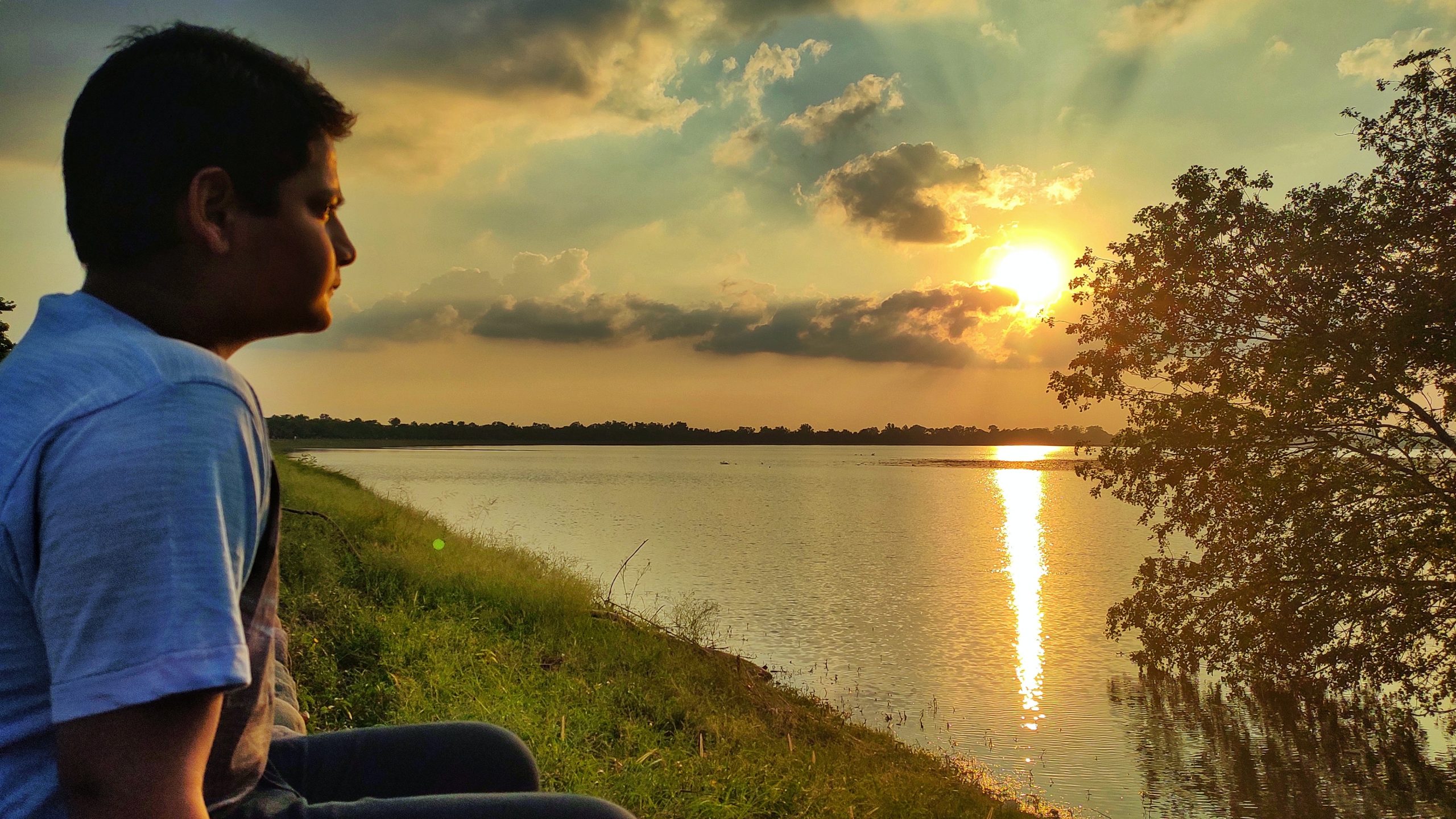 Boy sitting beside a lake