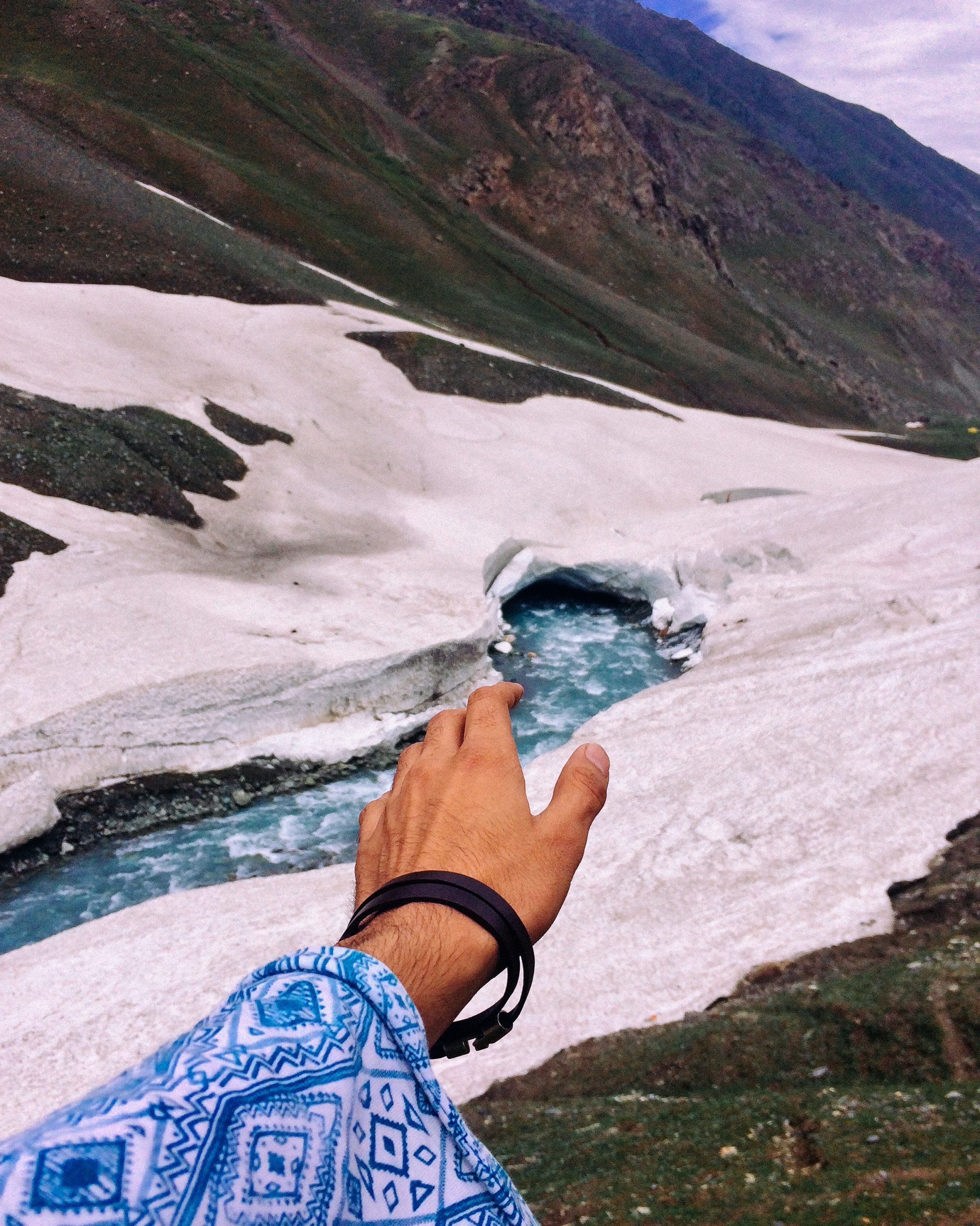 Male hand reaching towards mountain