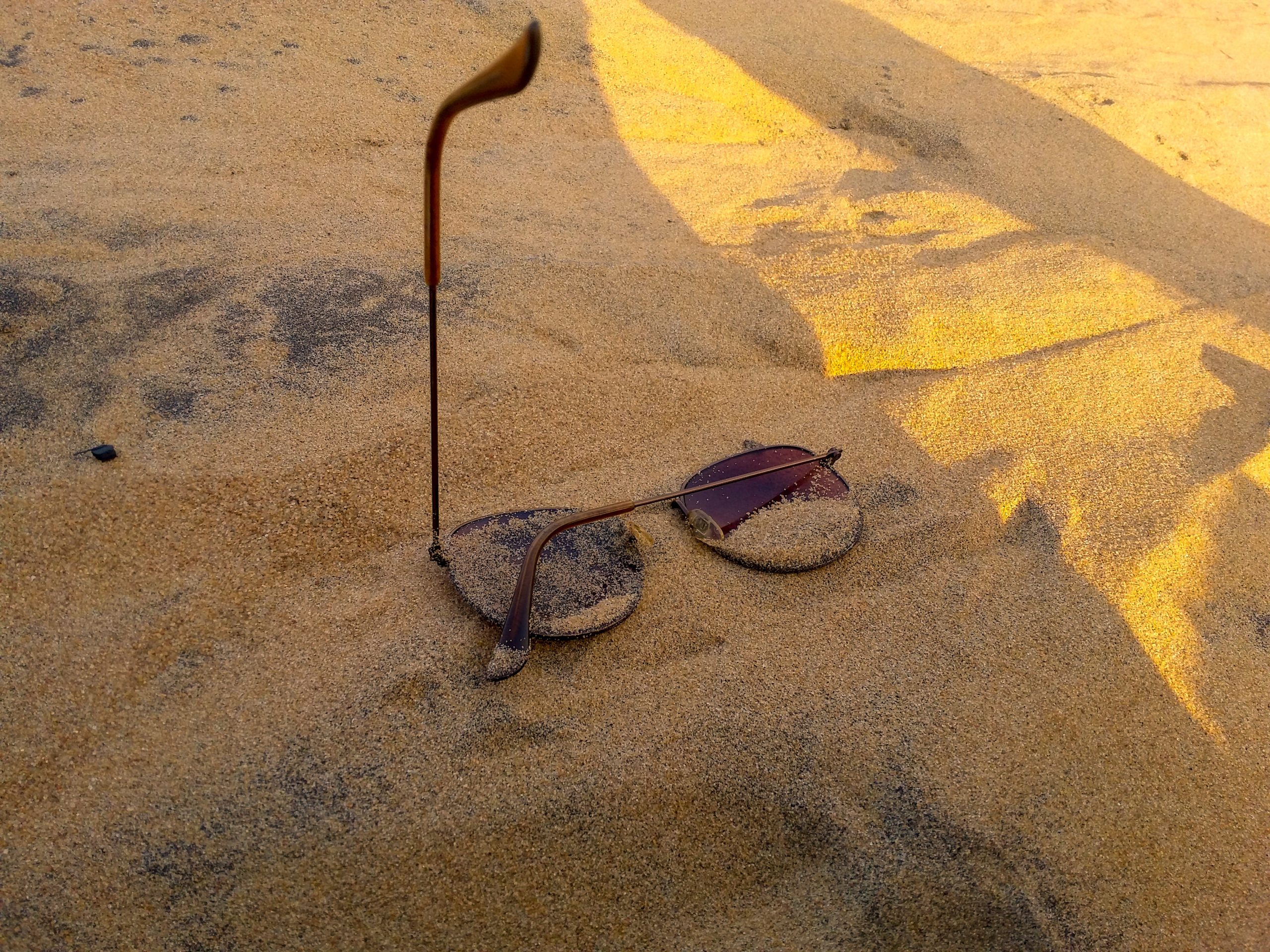 Sun glasses on sand near a beach