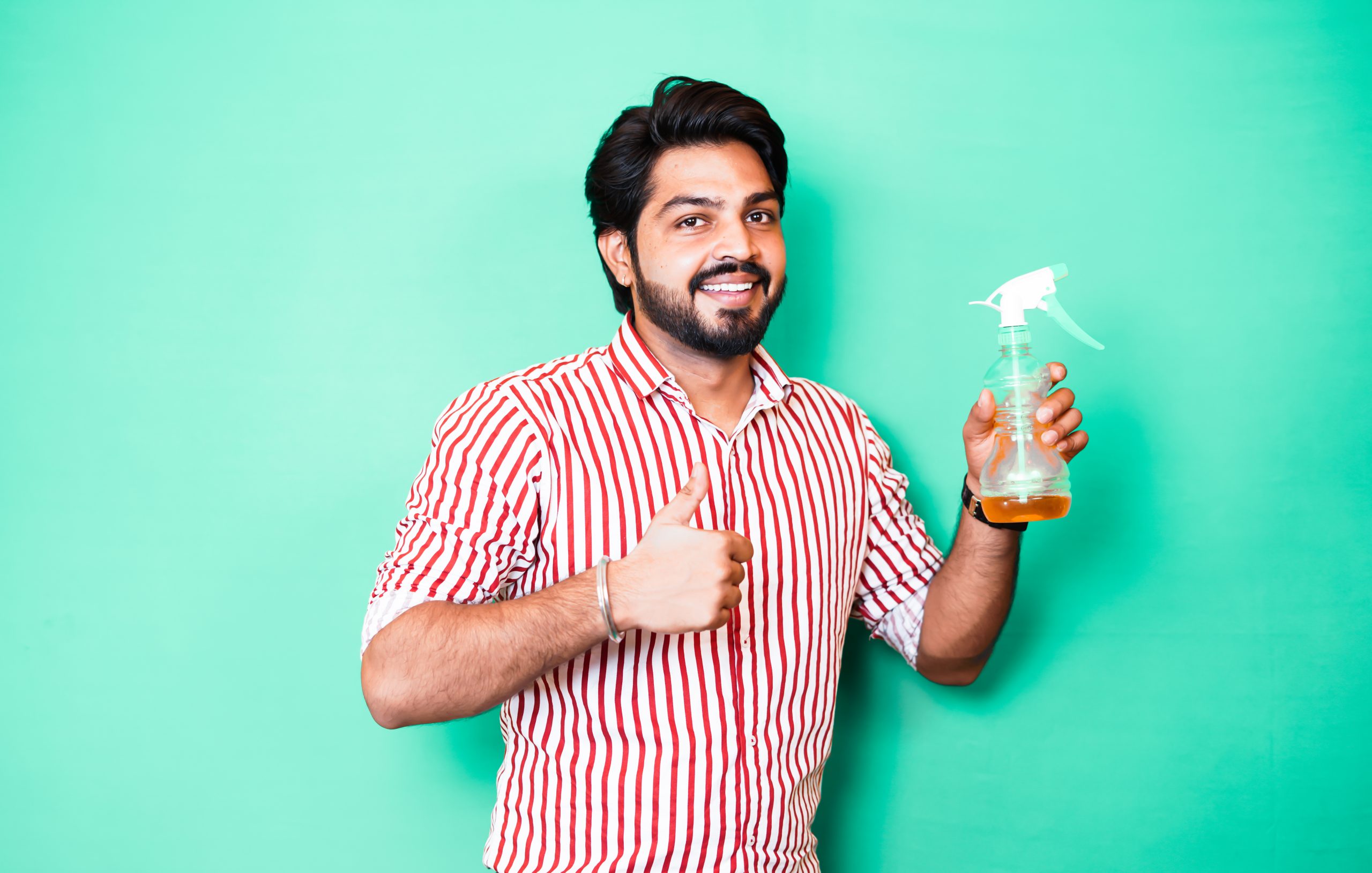 Young man holding hand sanitizer showing thumbs up