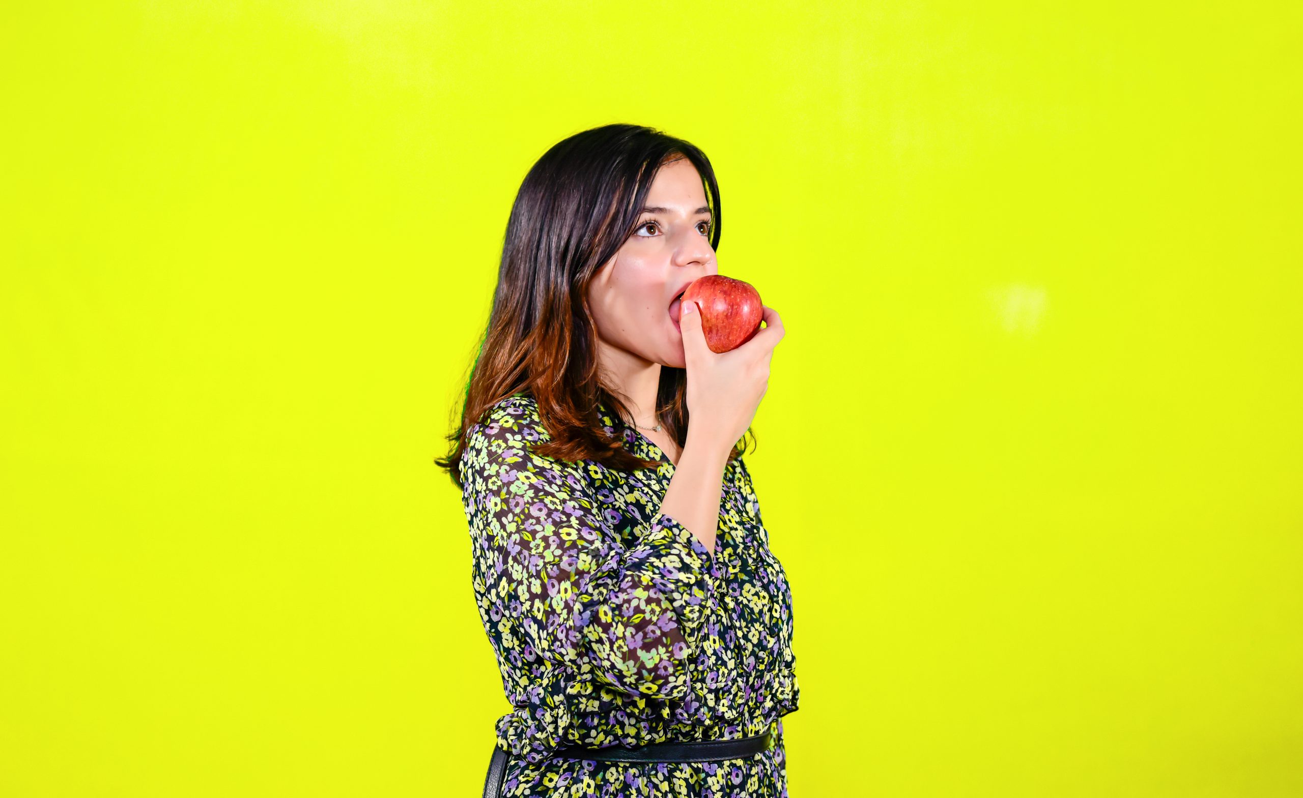 A Beautiful Girl Eating Apple in Yellow background