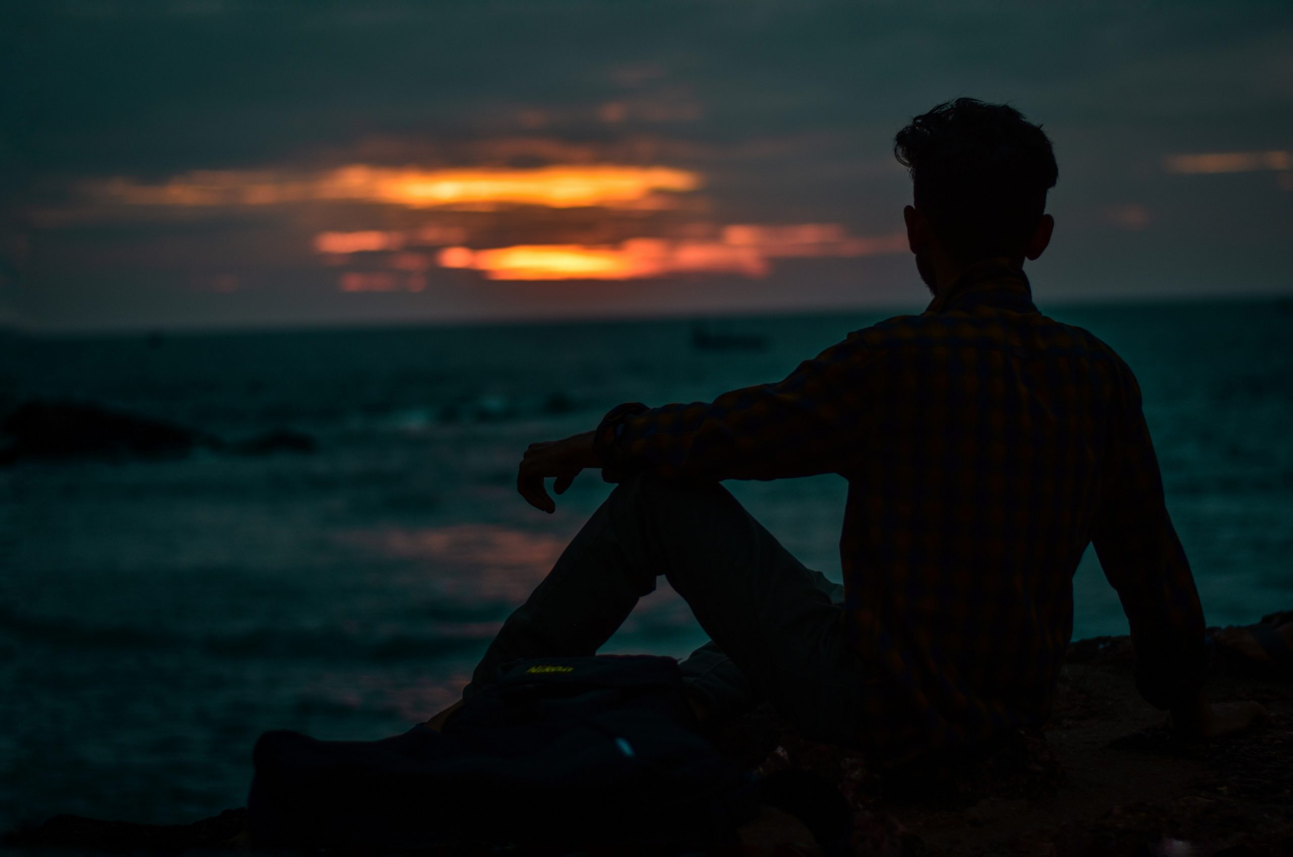 A boy facing sunset on a beach