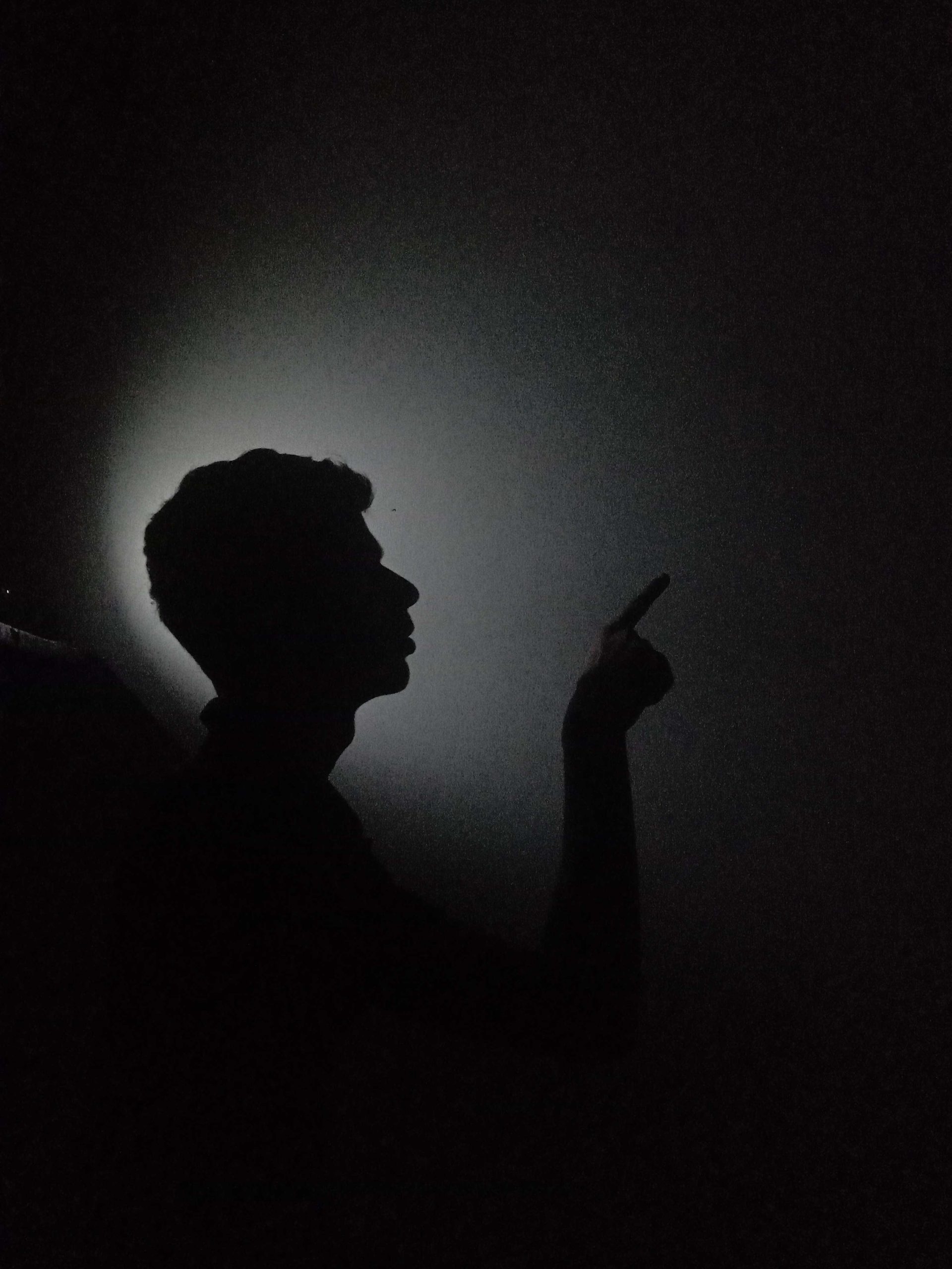 A boy pointing his finger in darkness
