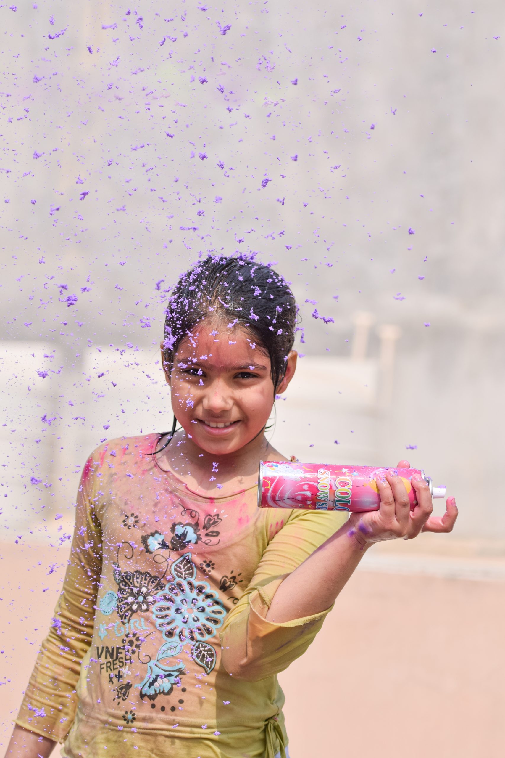 A little girl using foam spray on holi