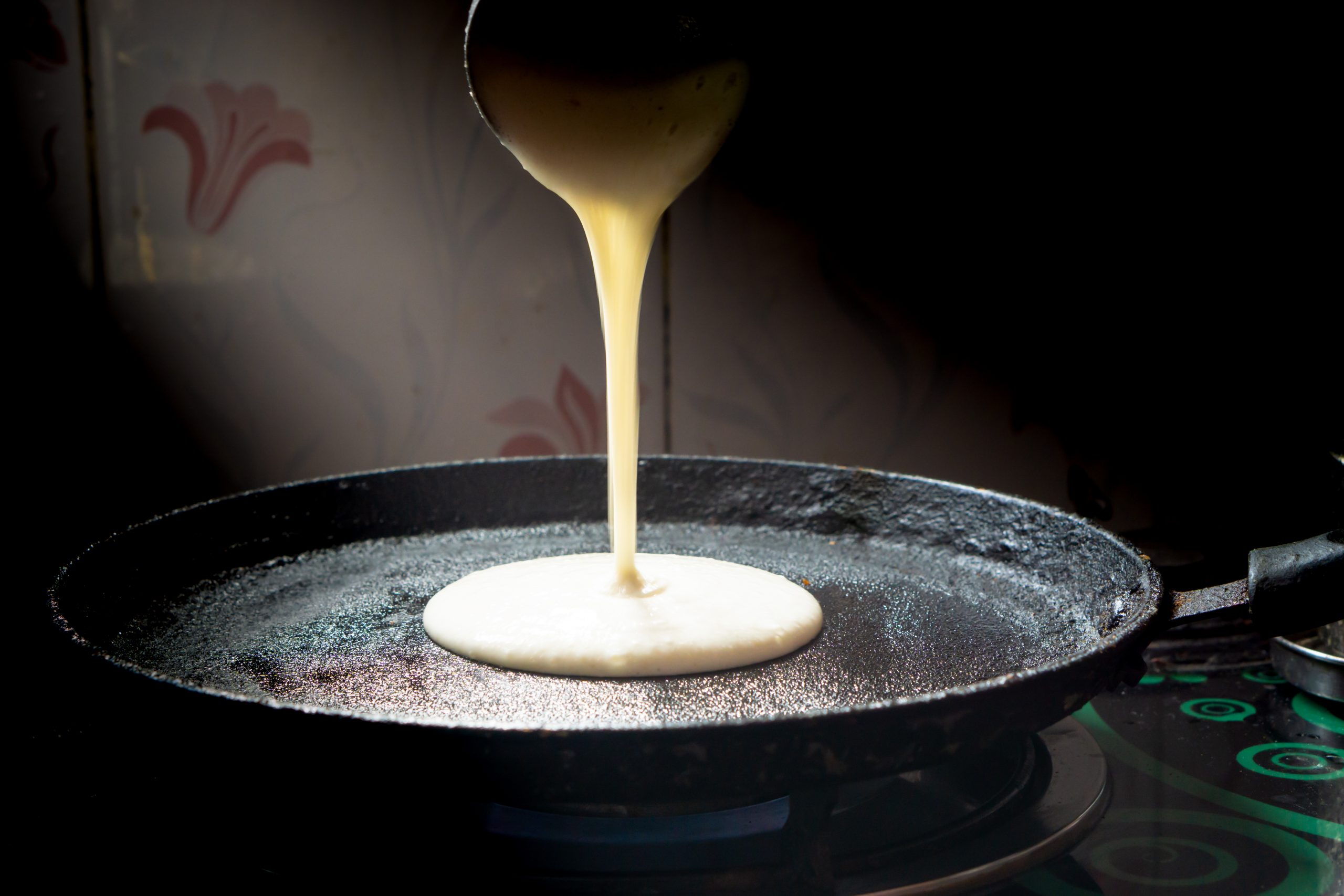 Dosa batter is being poured on pan