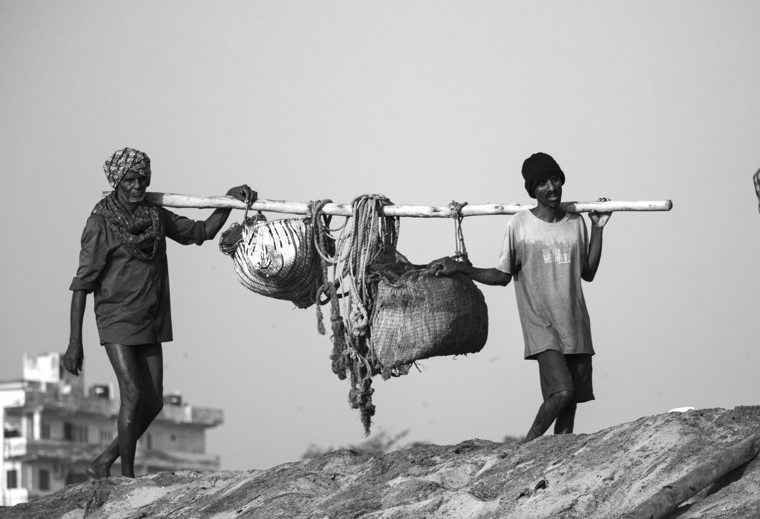 Fishermen carrying load of fish on shoulder