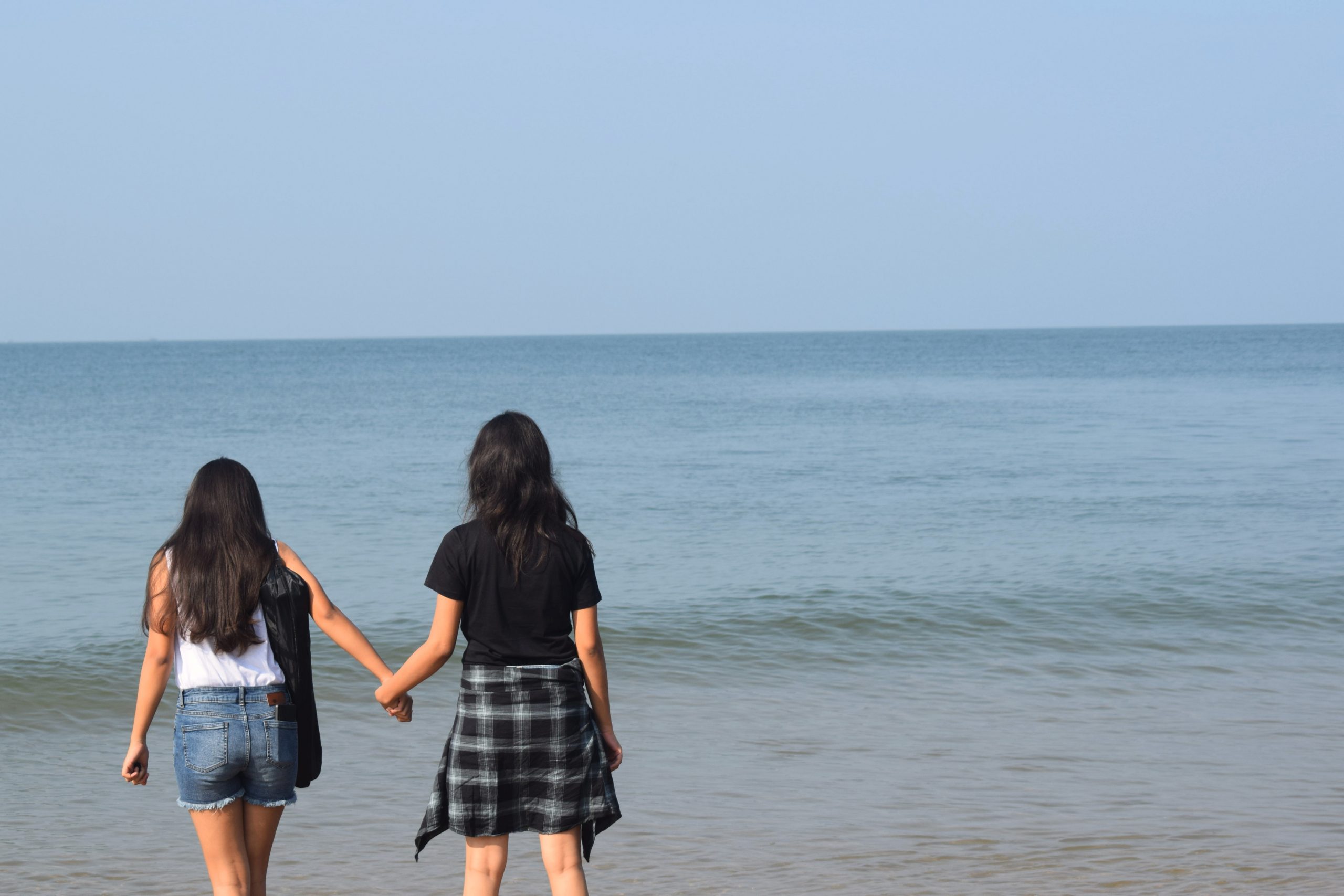 Two girls holding hands at a beach