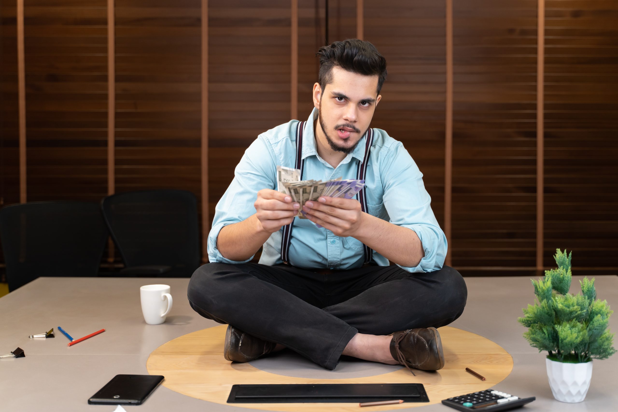 Young male counting money in office