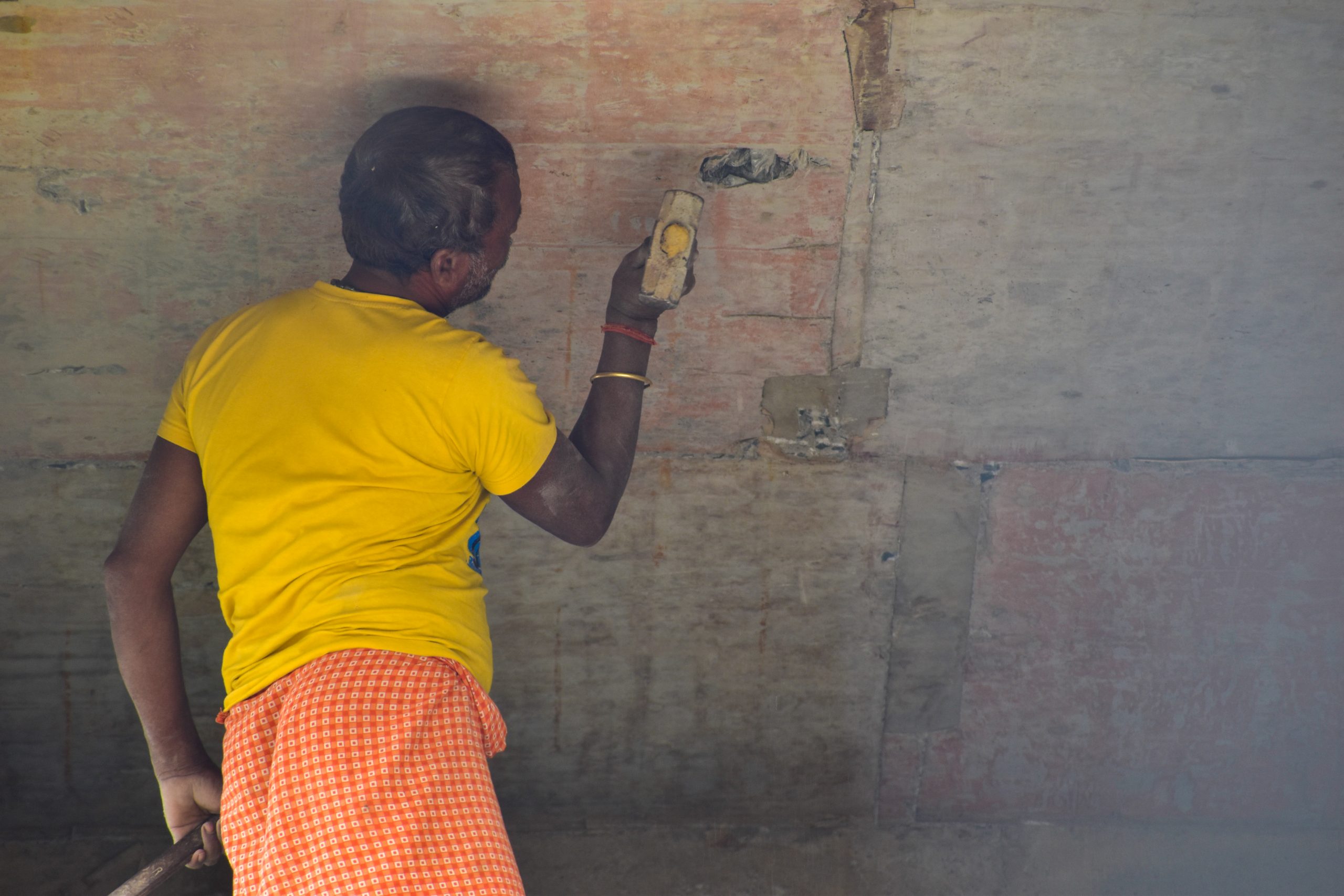 A man hammering on a wall