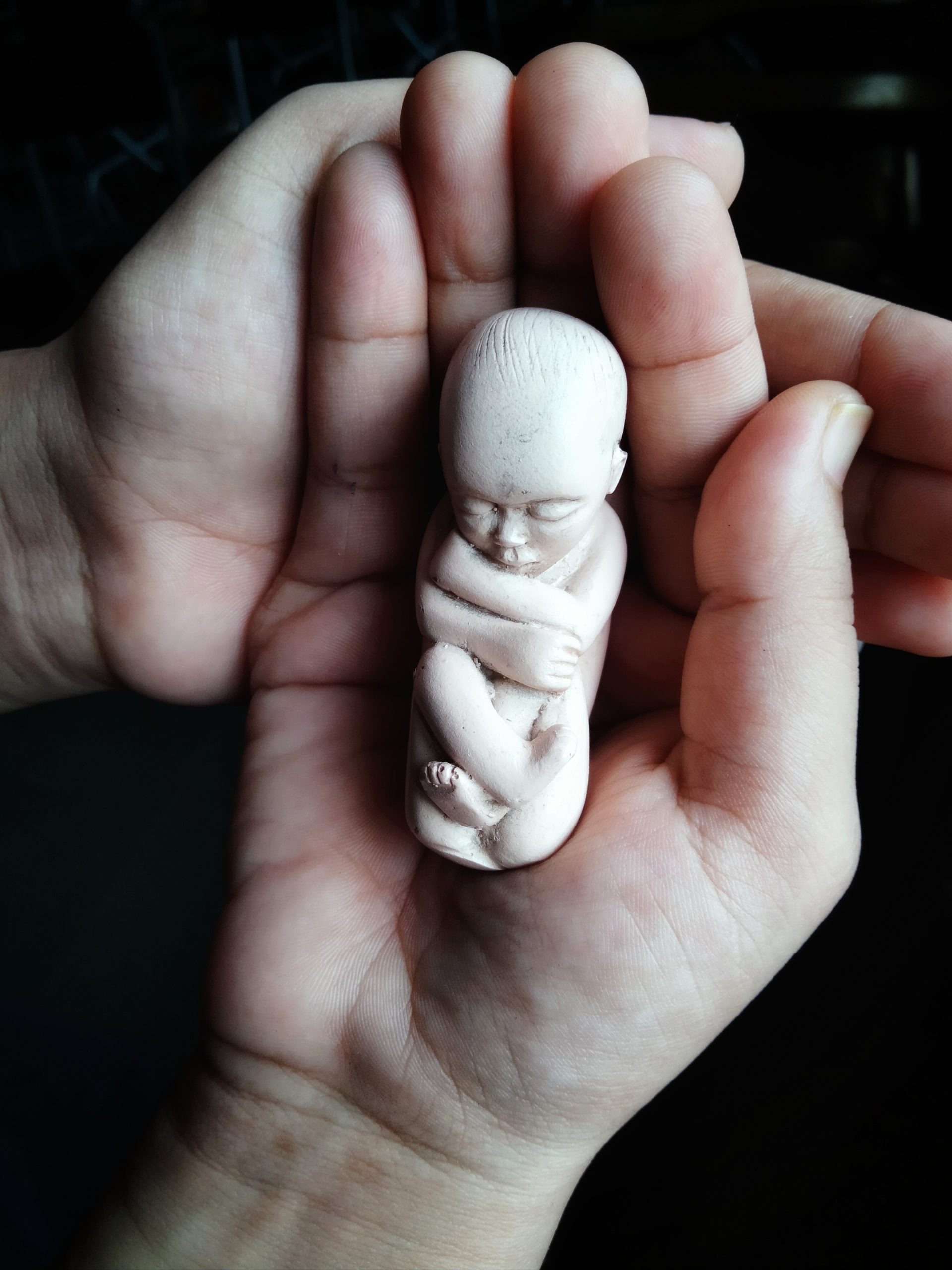 A tiny statue of baby in hand