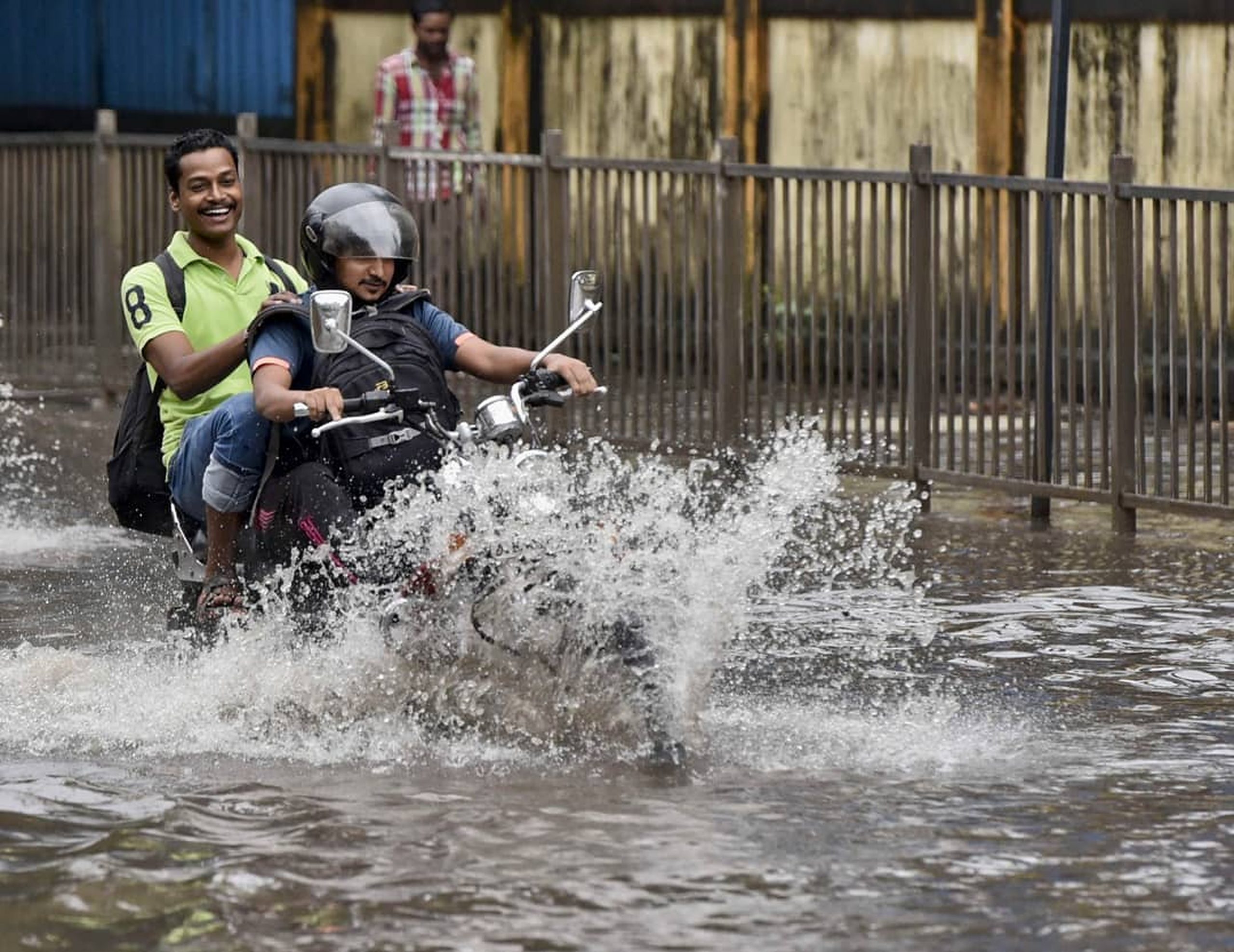 men riding a bike in water logged roads