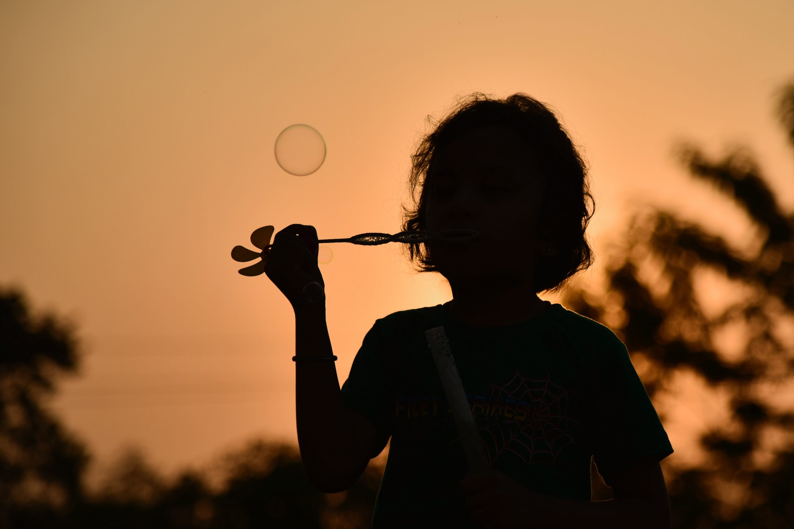 silhouette of girl blowing bubbles