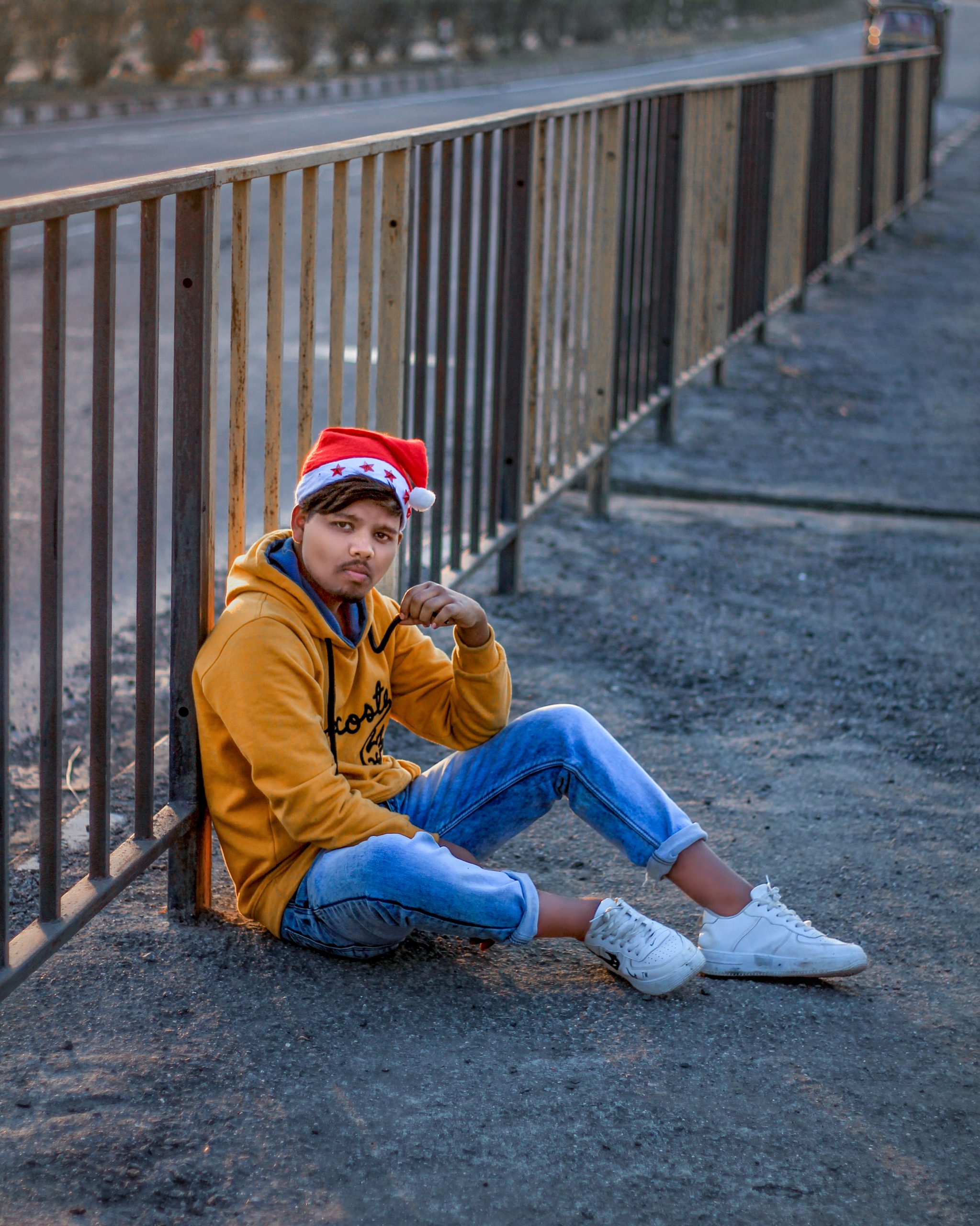 A boy sitting near a fence