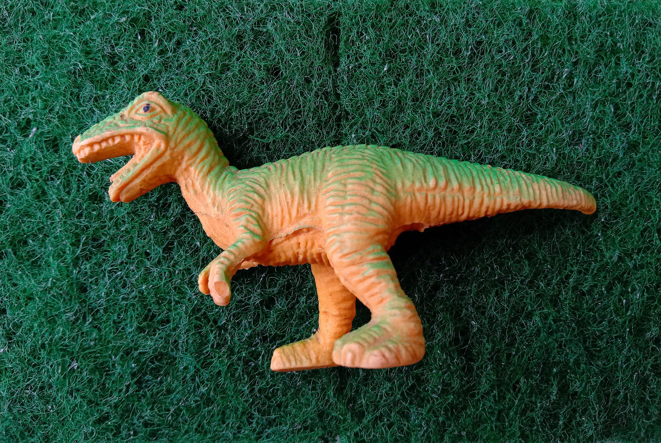 Toy Dinosaur lying on a carpet.