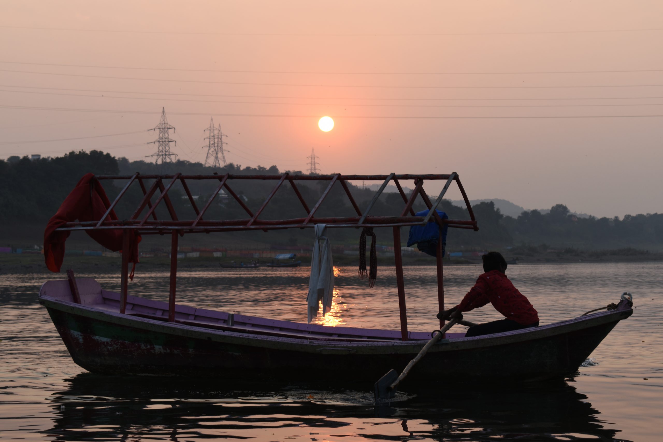 man paddeling boat in water during sunset