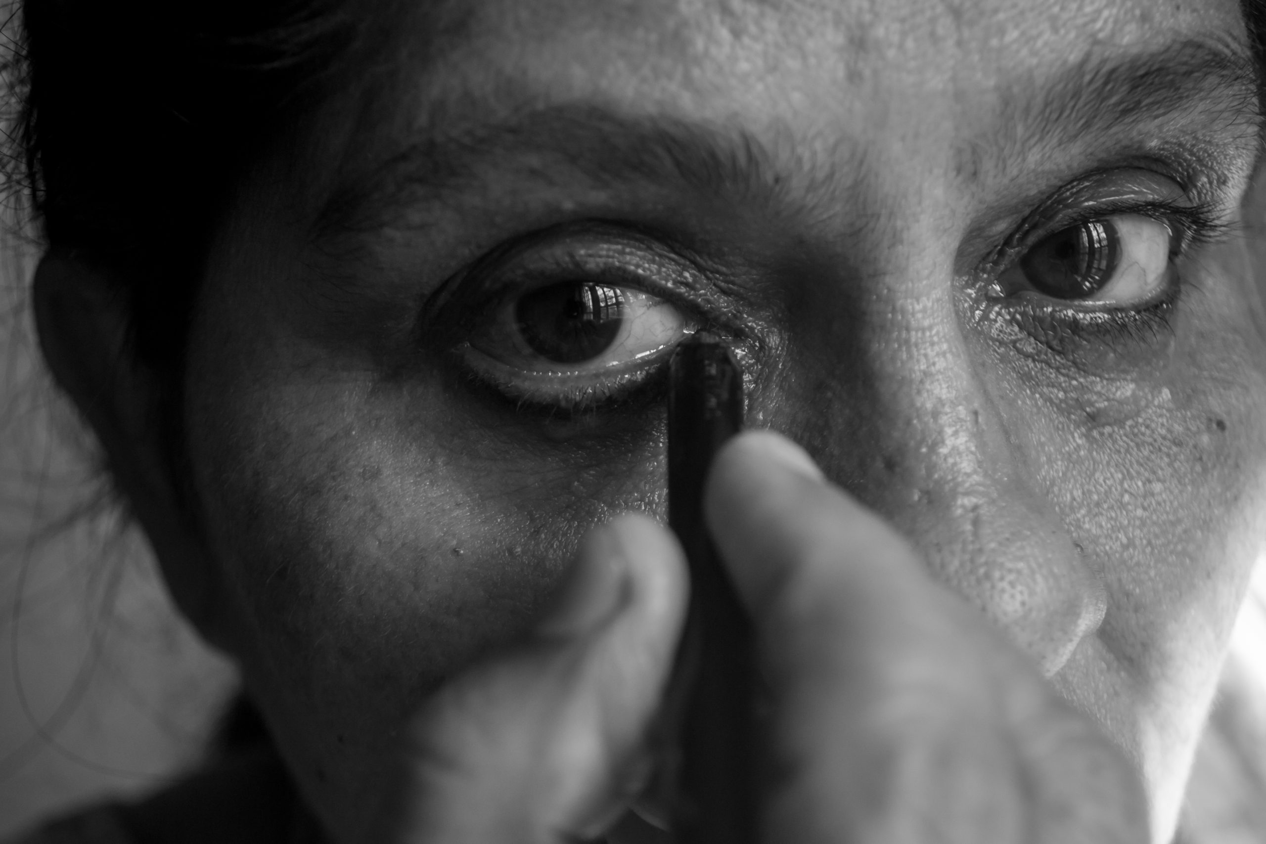 A woman applying eye liner