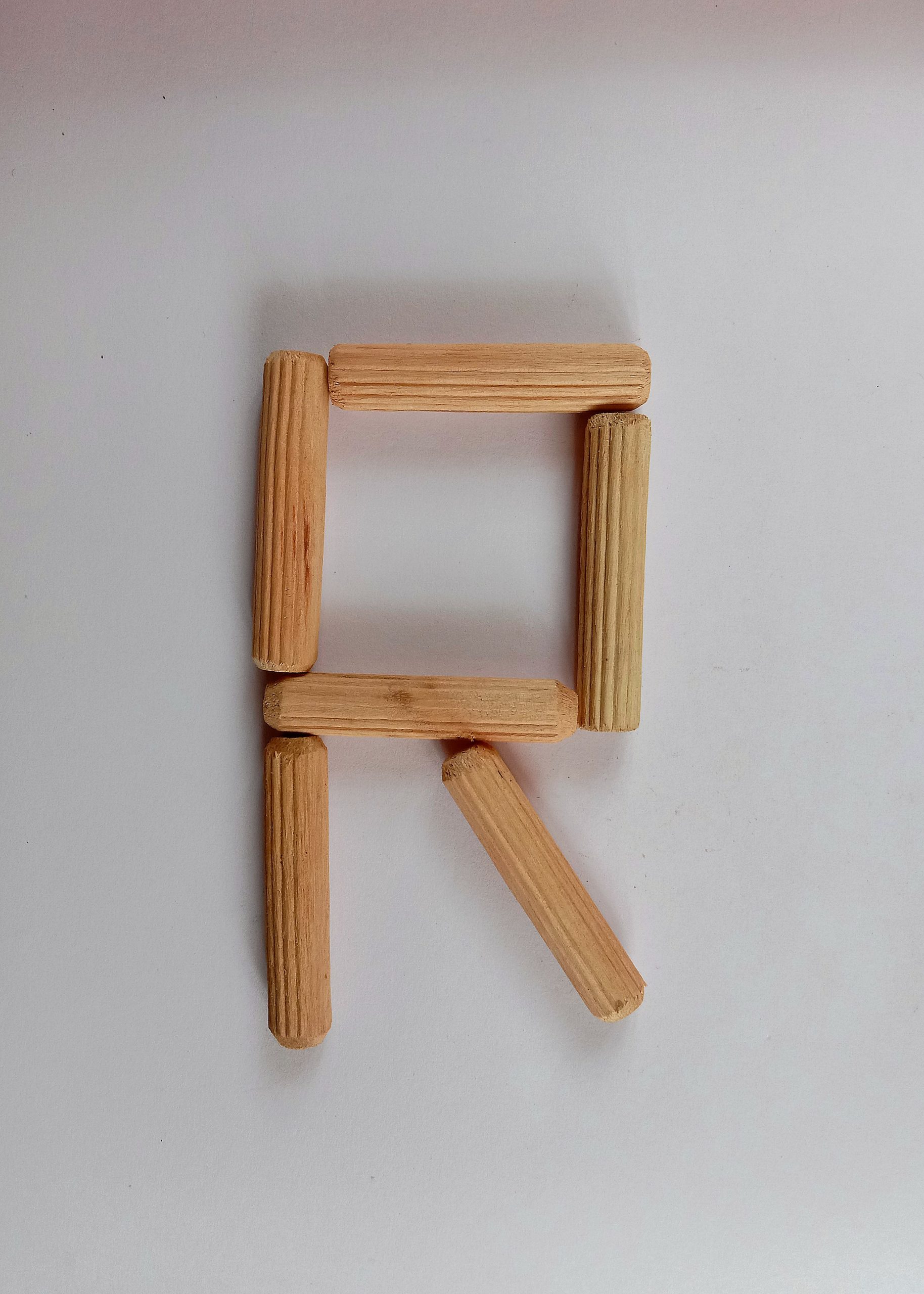 Letter R written with wooden sticks