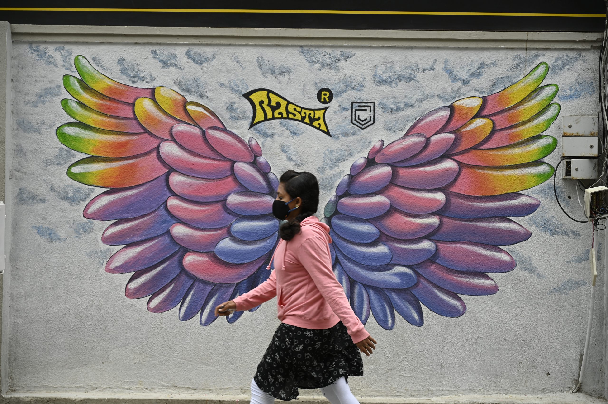 A girl walking along a painted wall