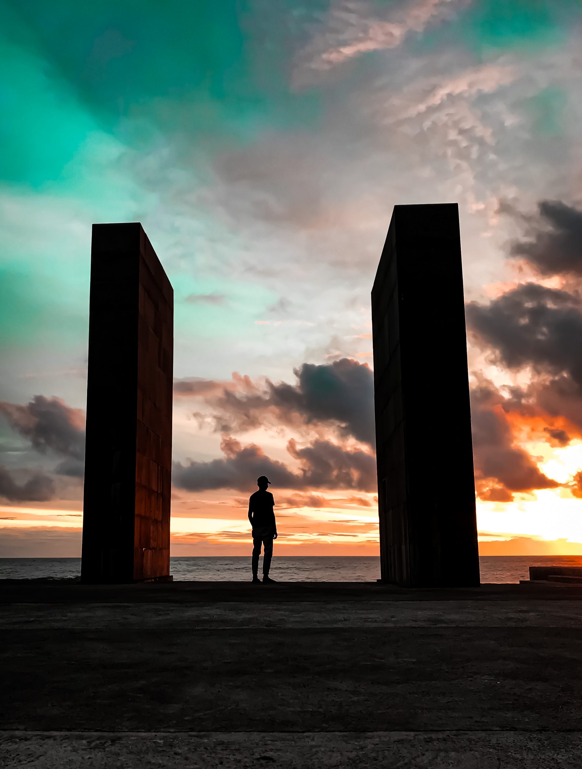 Guy standing in between two pillars at beach