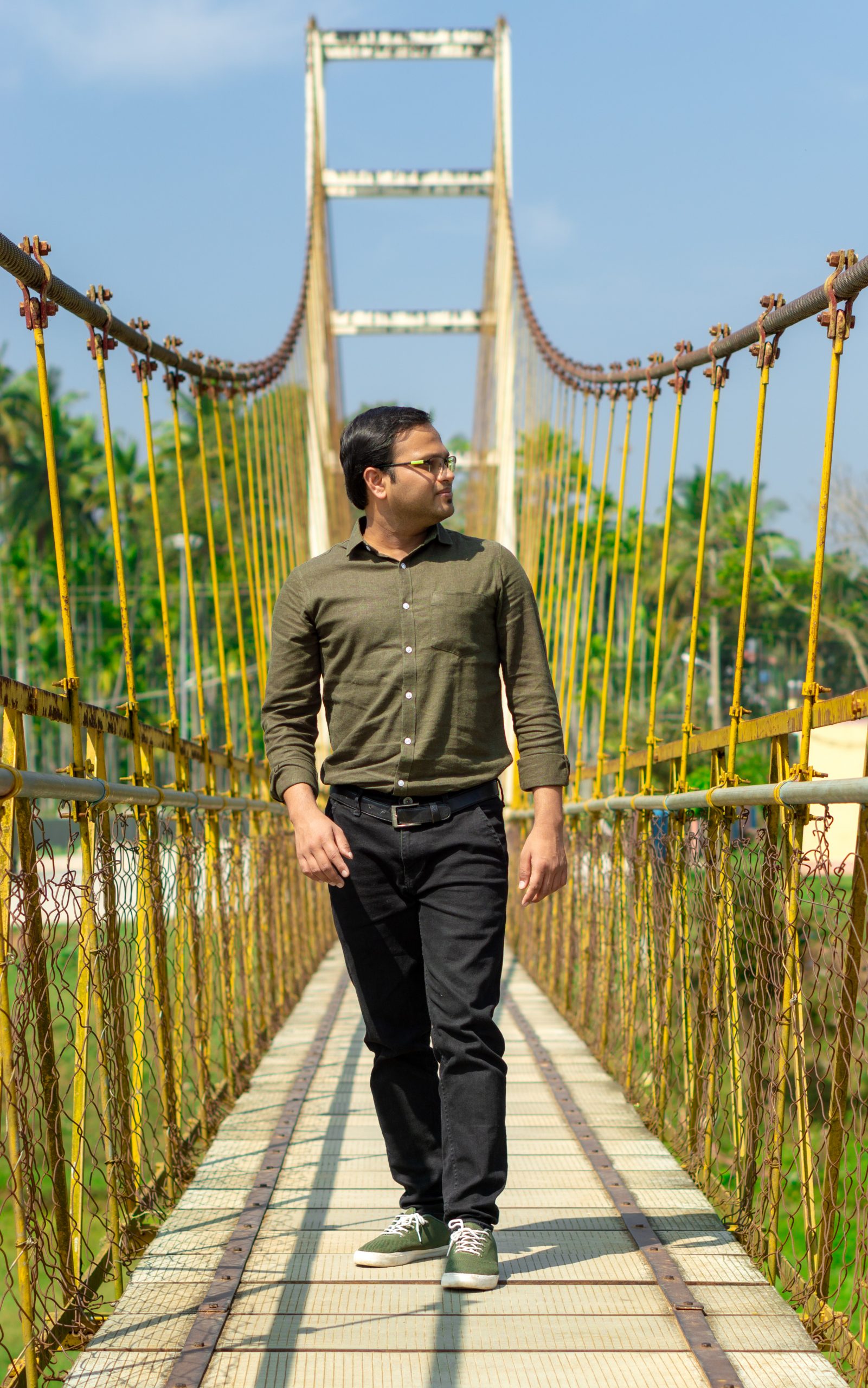 A person posing on a hanging bridge