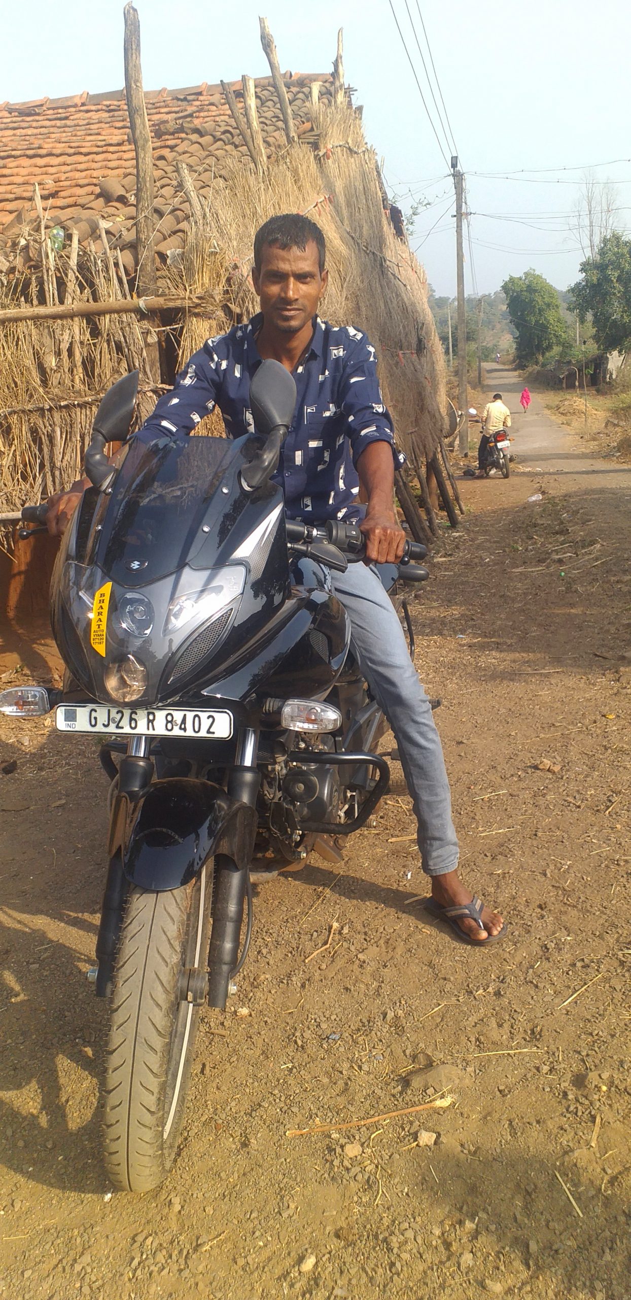 Boy posing bike near hut in village