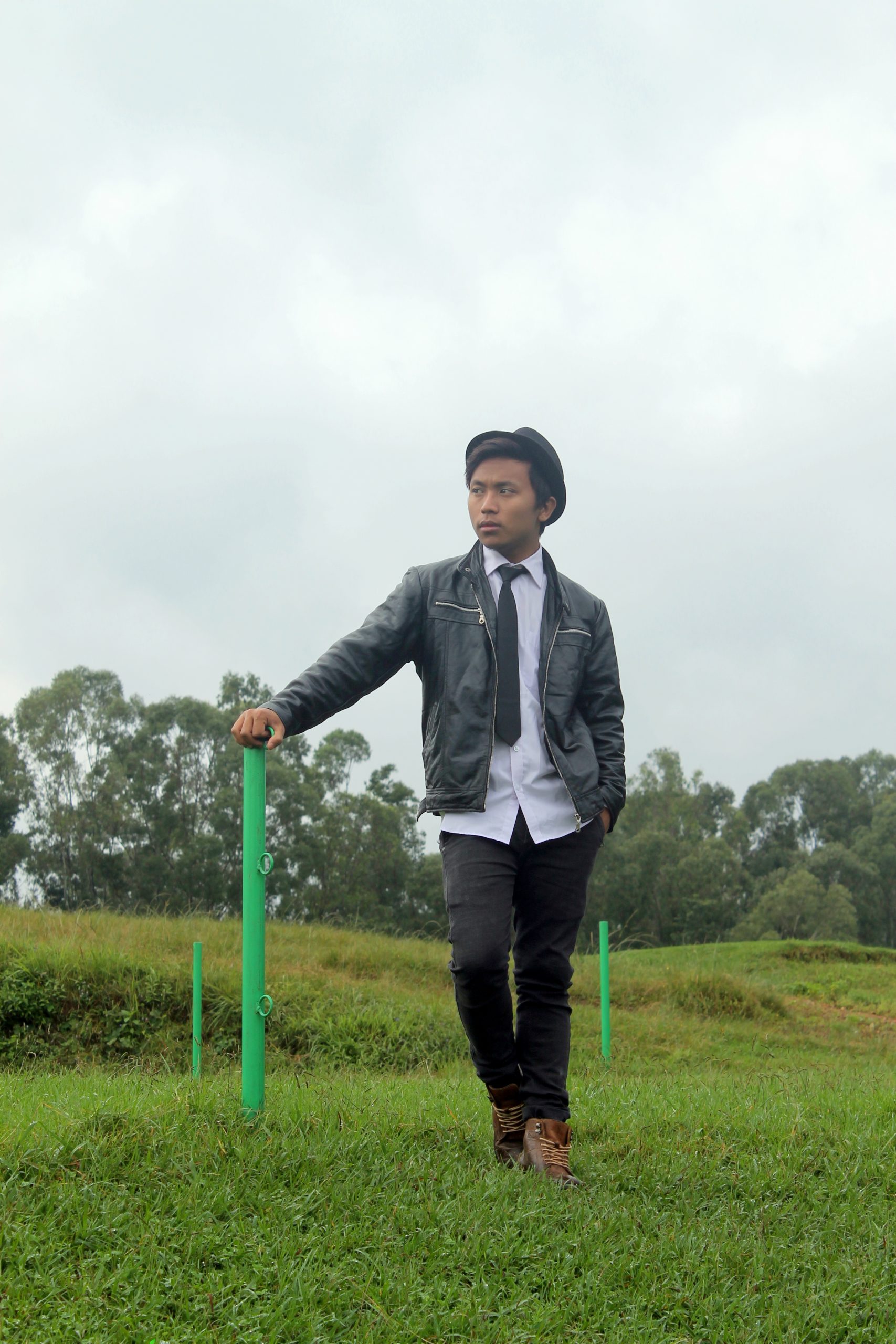 Boy posing in garden while holding pole