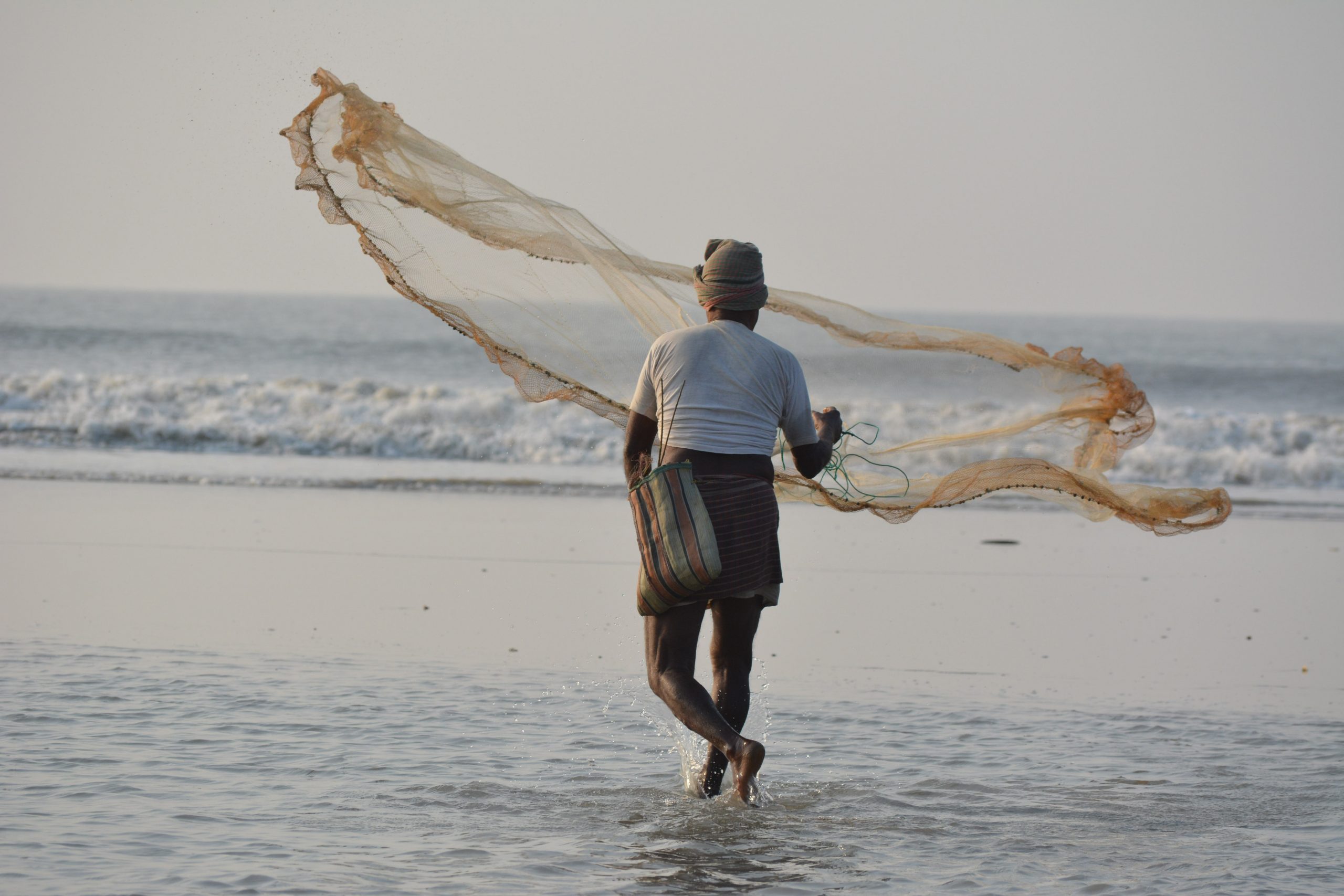 A fisherman spreading his net in water