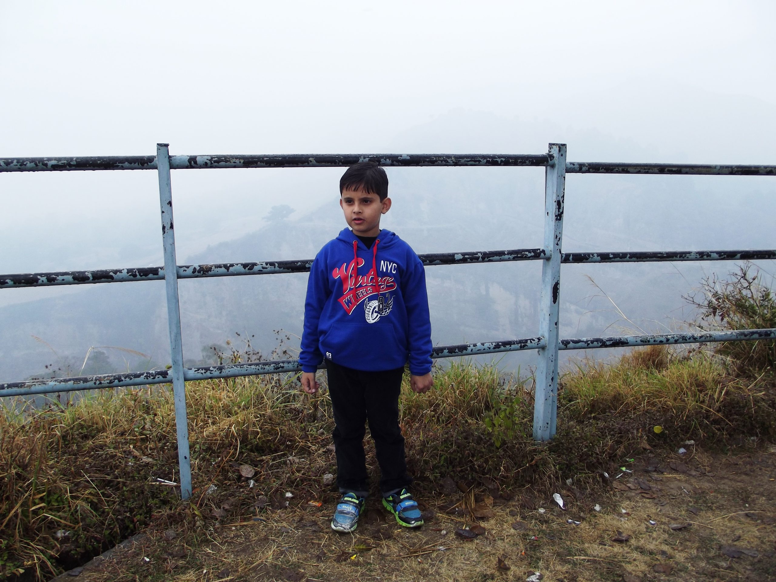 Kid standing against an iron grill