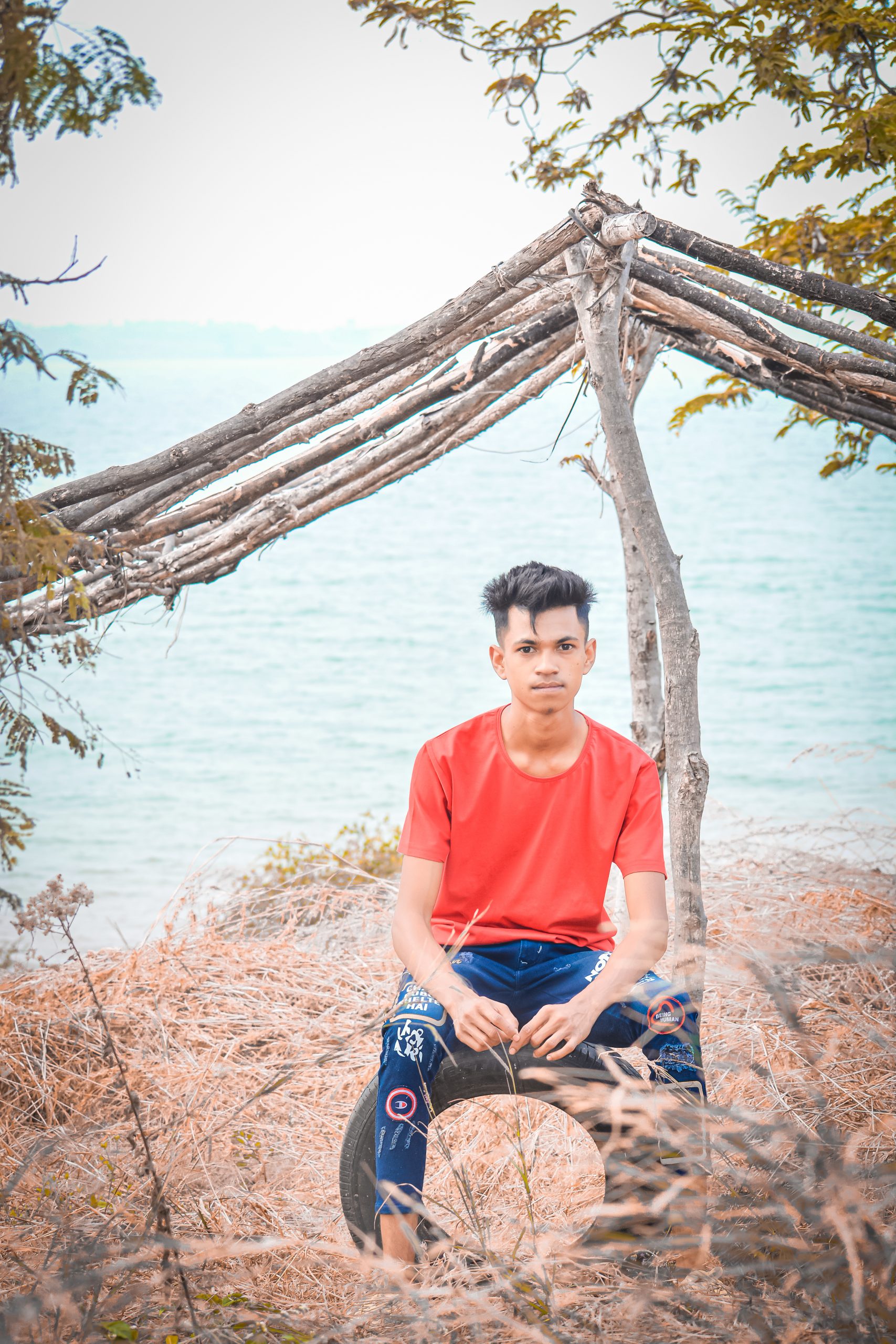 Boy sitting on tyre near the sea