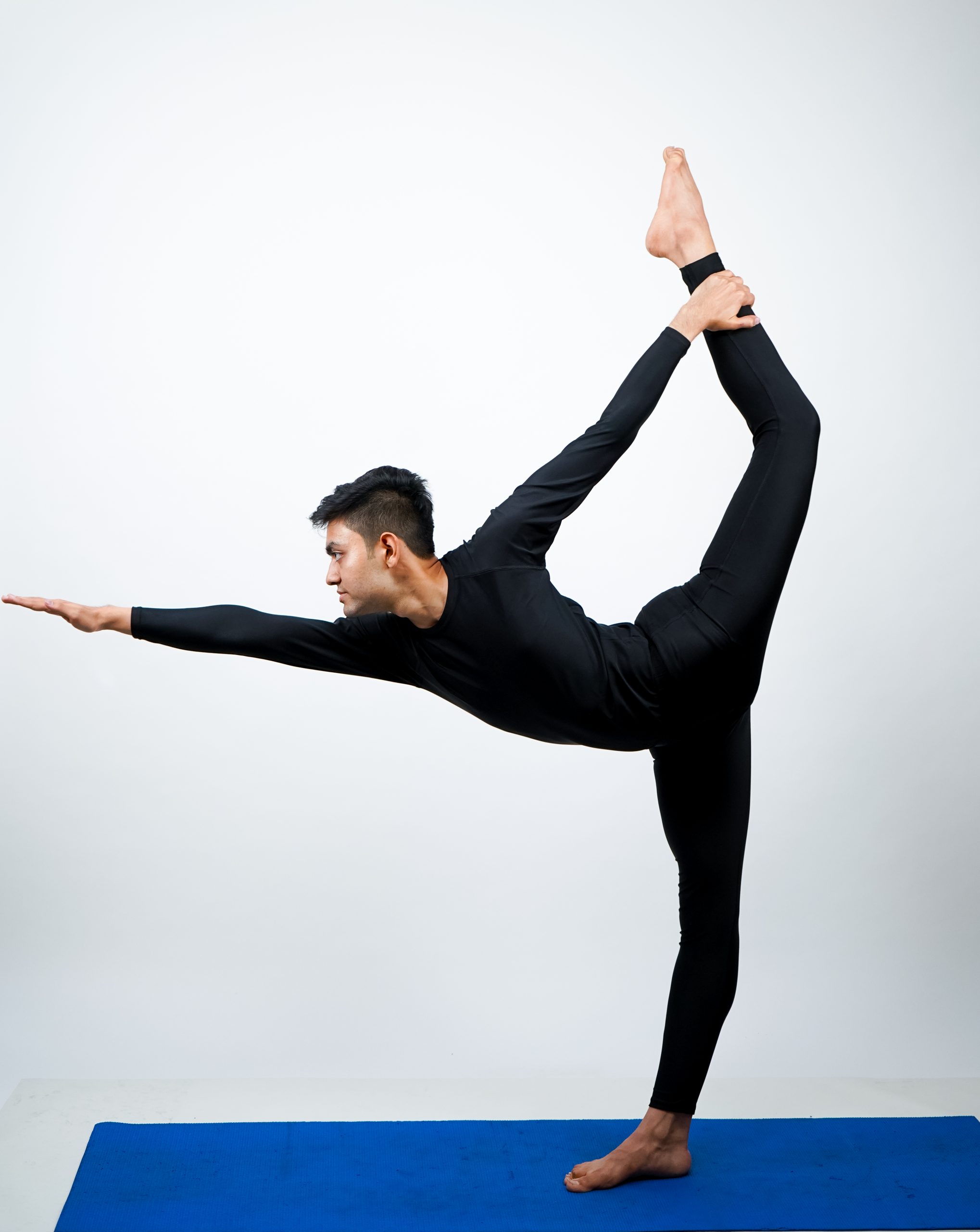 A person in Natarajasana, with arms and leg outstretched, performing a yoga pose