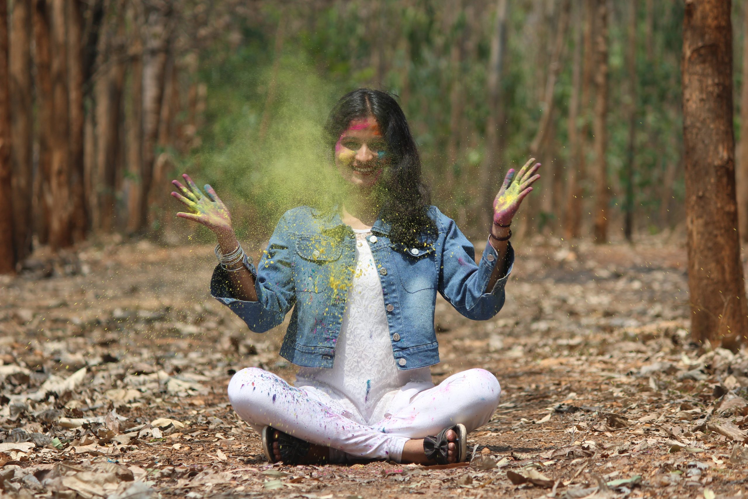A girl in jungle playing with Holi colors