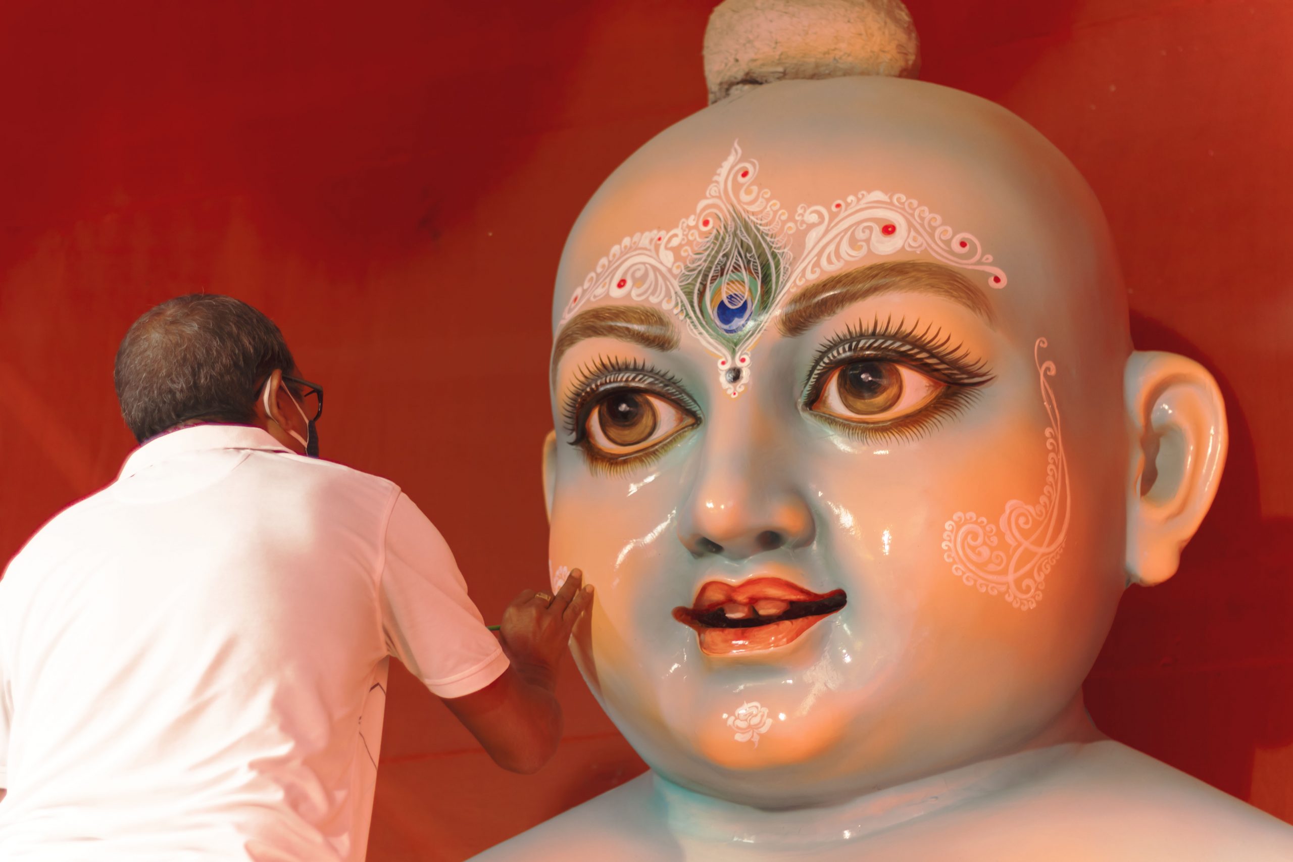A man near a statue of Lord Krishna