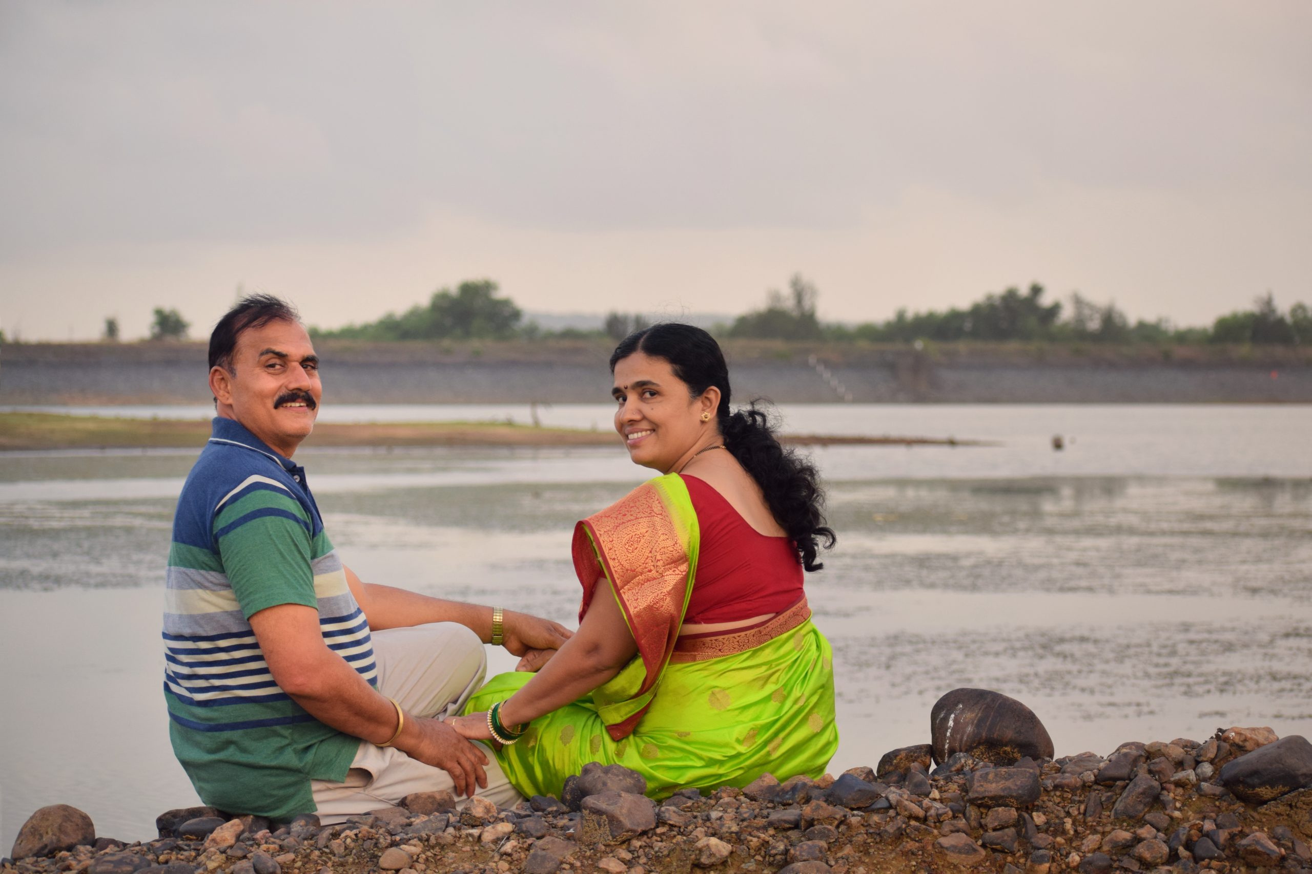 Indian happy couple sitting near a lake