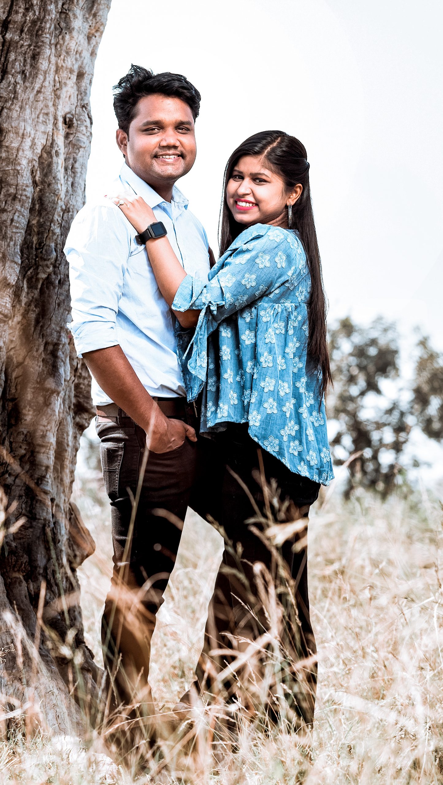 Couple posing by the side of tree