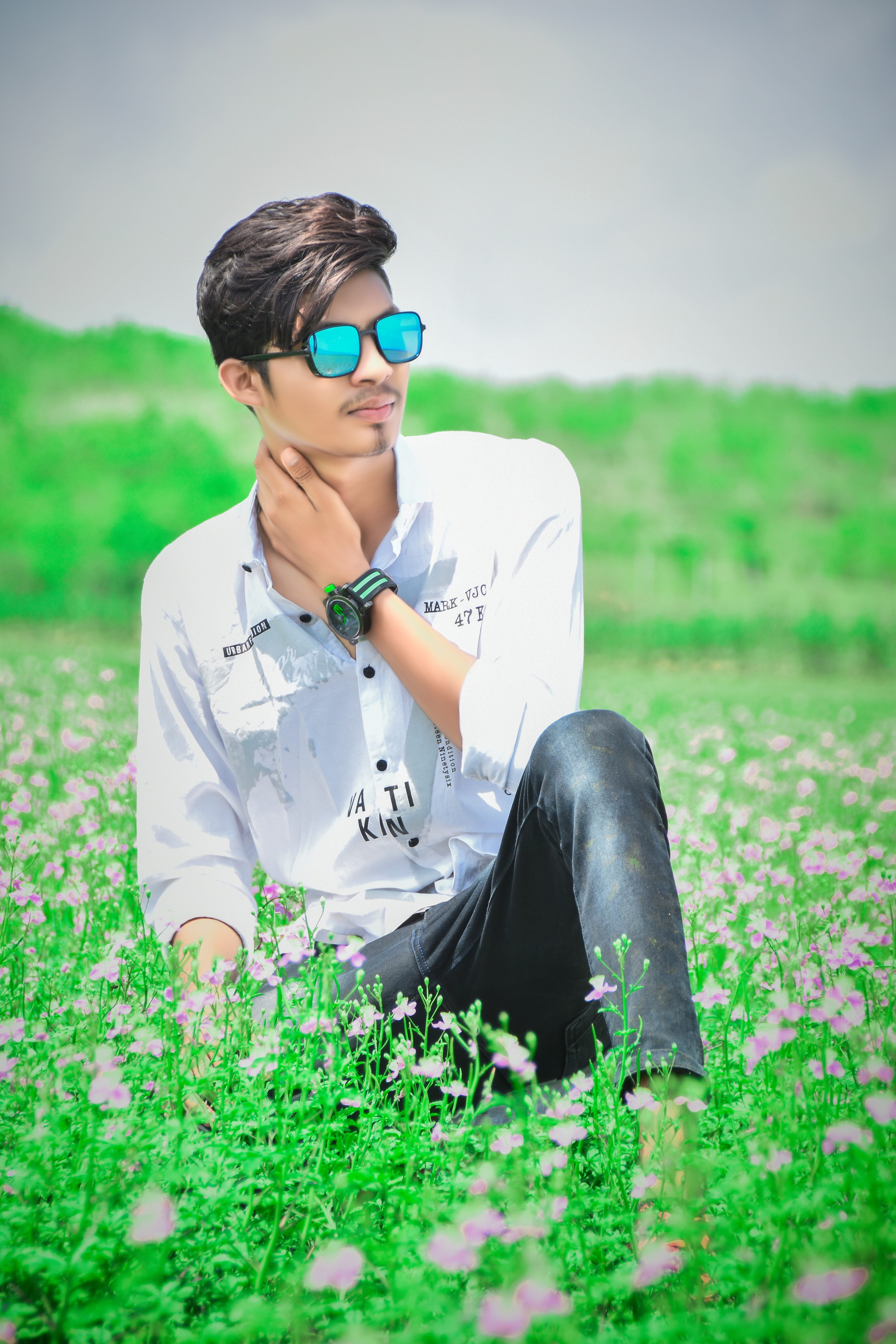 A boy sitting on grass flowers