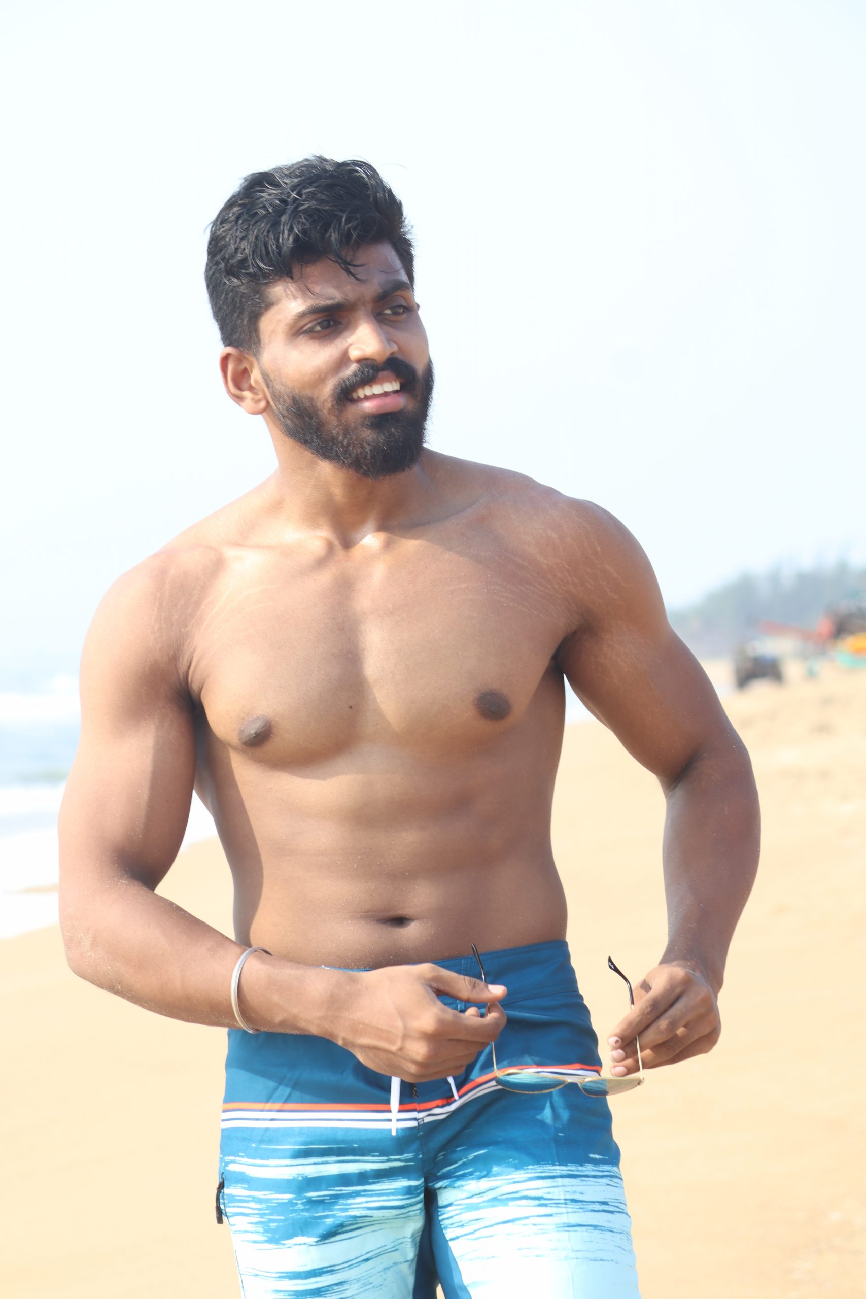 Boy showing his arms and muscles on the beach