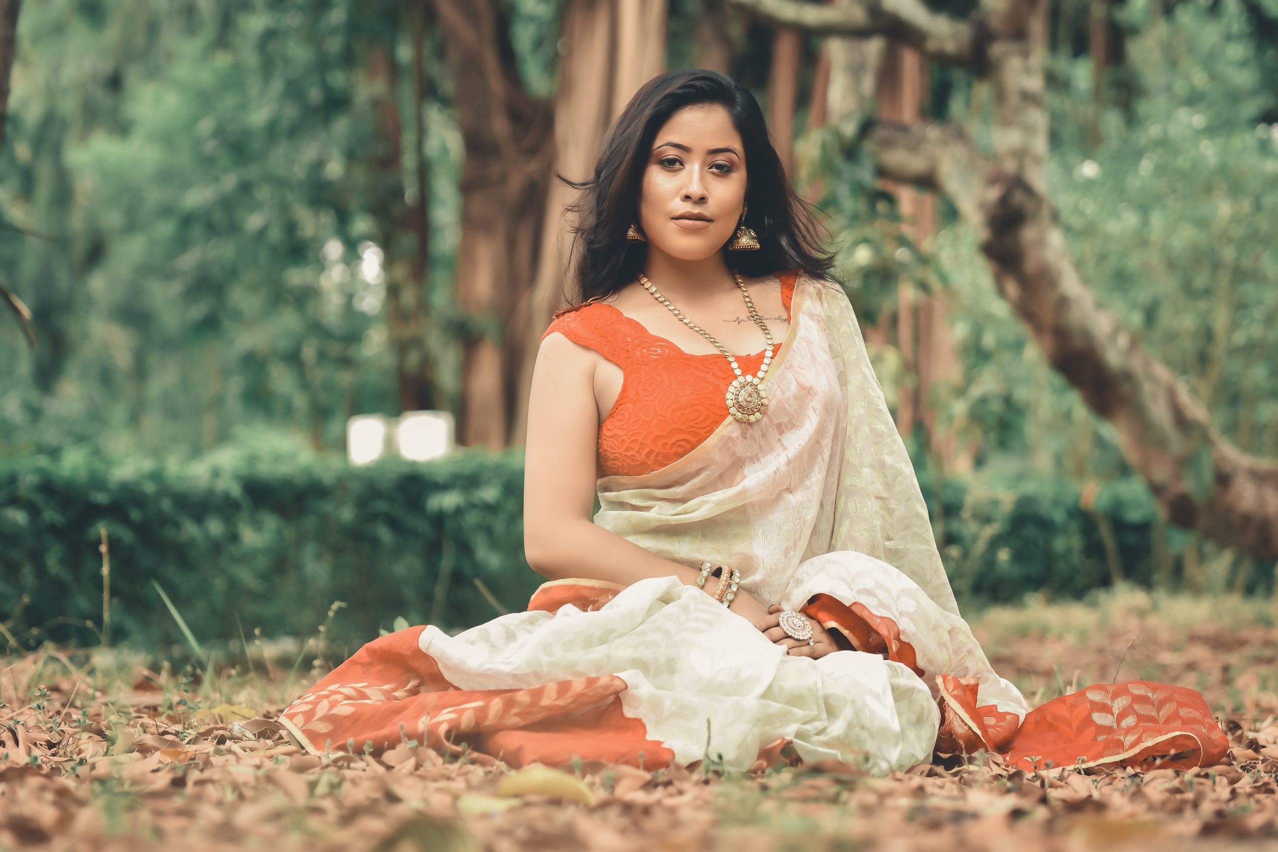 Female model posing in the forest while wearing saree