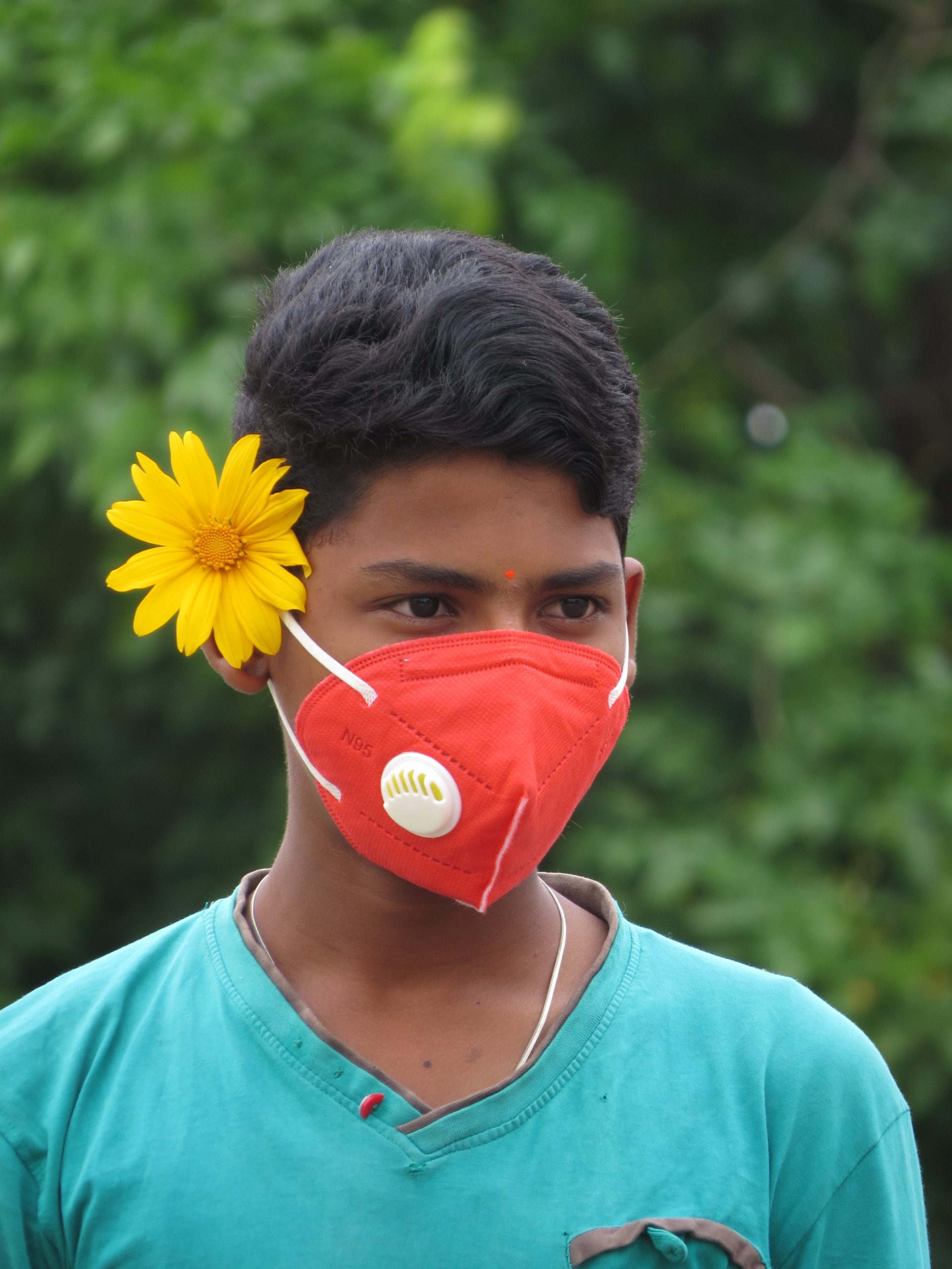 A boy with face cover and a flower