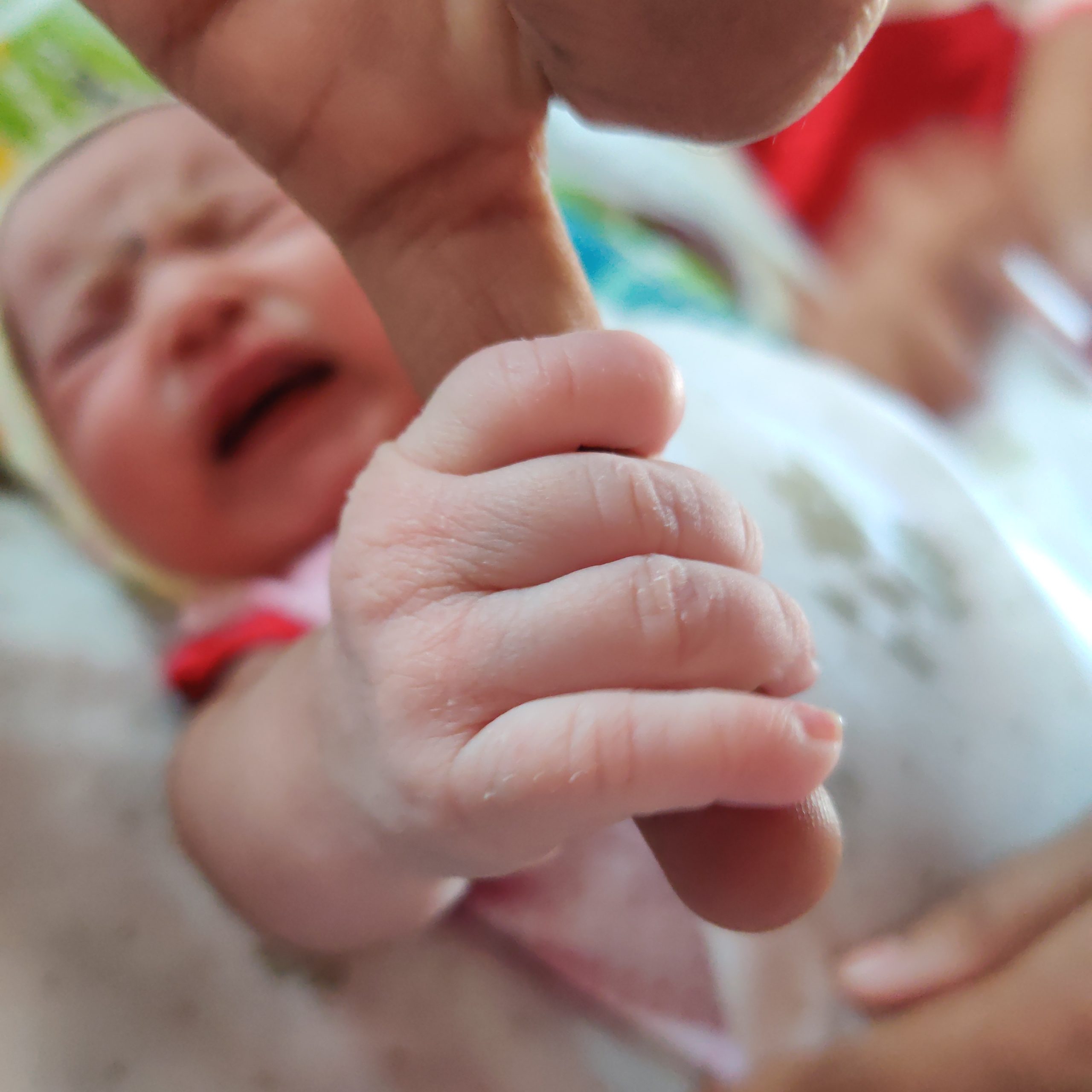 A newborn baby holding mother's finger